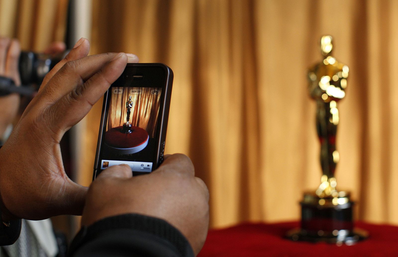 Un hombre fotografía un Oscar en una exposición en Nueva York