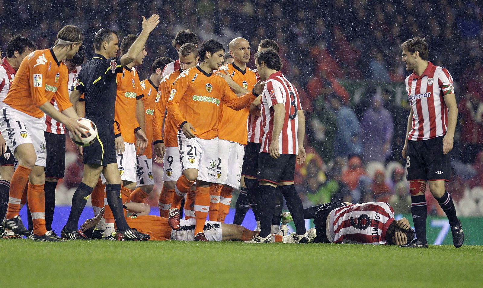 Los jugadores del Athletic de Bilbao y del Valencia rodean a Fernando Llorente y David Navarro, ambos en el suelo.