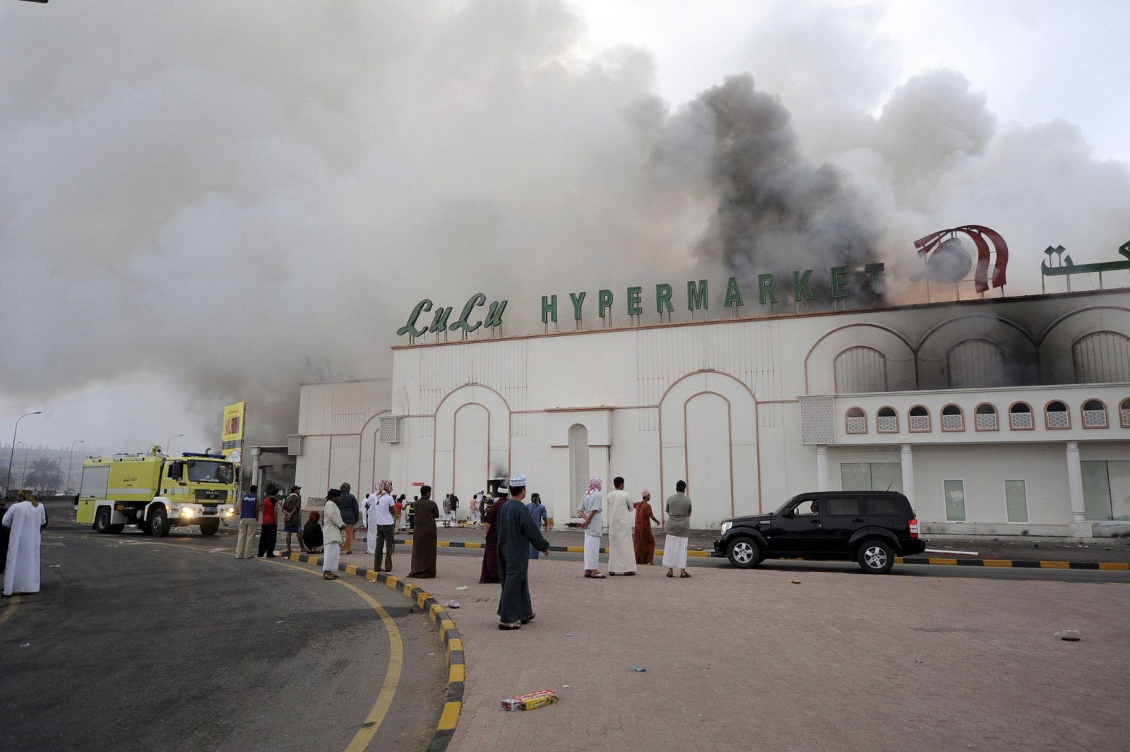 Los bomberos intentan extinguir el incendio en un supermercado en Sohar, Omán, incendiado durante las protestas