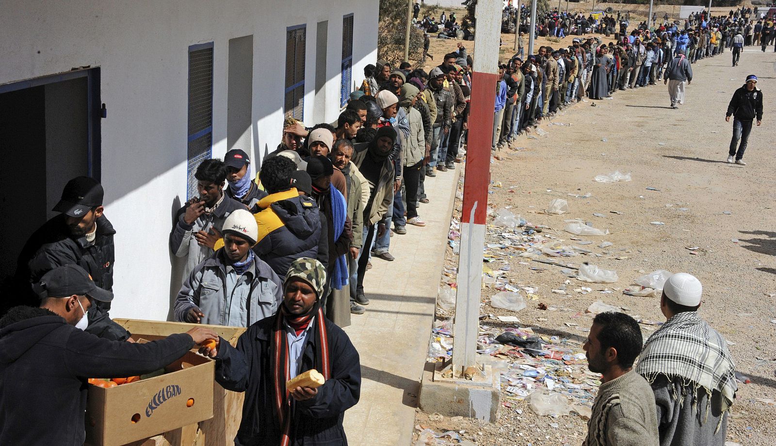 Refugiados que abandonan Libia reciben pan en el paso fronterizo de Ras el Jebir (Túnez)