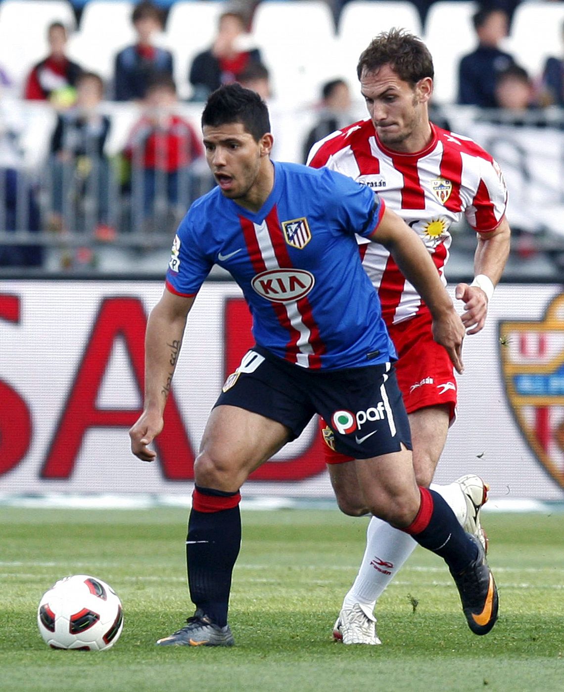 El delantero argentino del Atlético de Madrid Sergio "Kun" Agüero (i) conduce el balón presionado por el defensa del UD Almería Carlos García