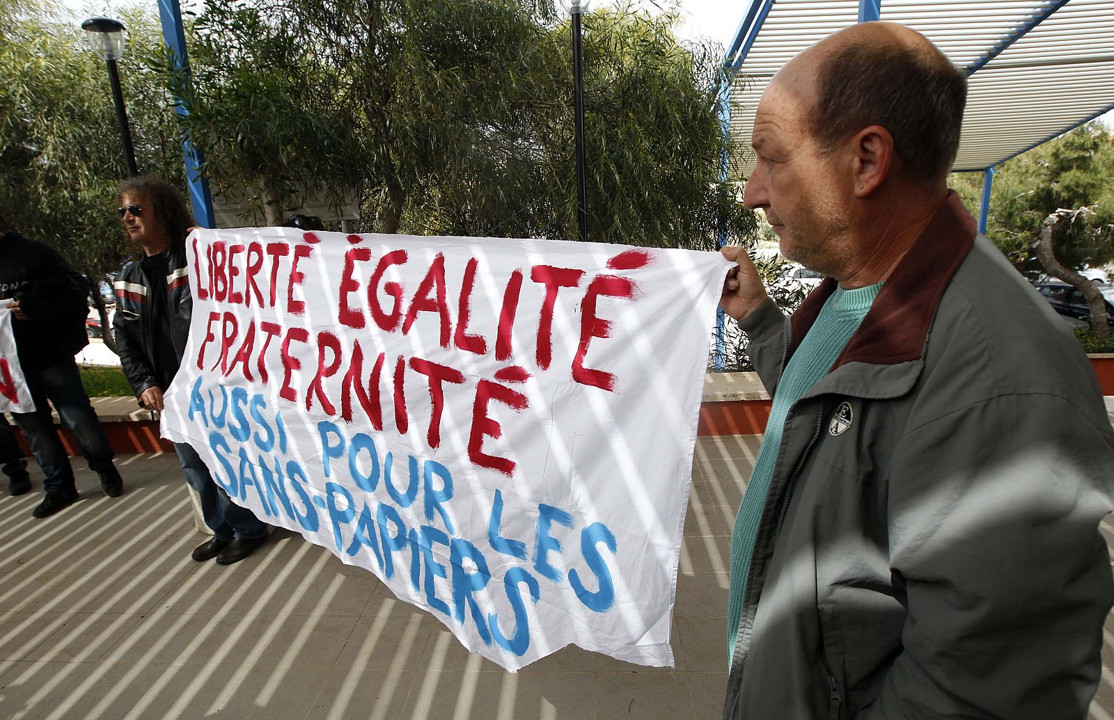Ciudadanos de Lampedusa portan una pancarta ante la llegada de la líder del partido de extrema derecha Marine Le Pen.