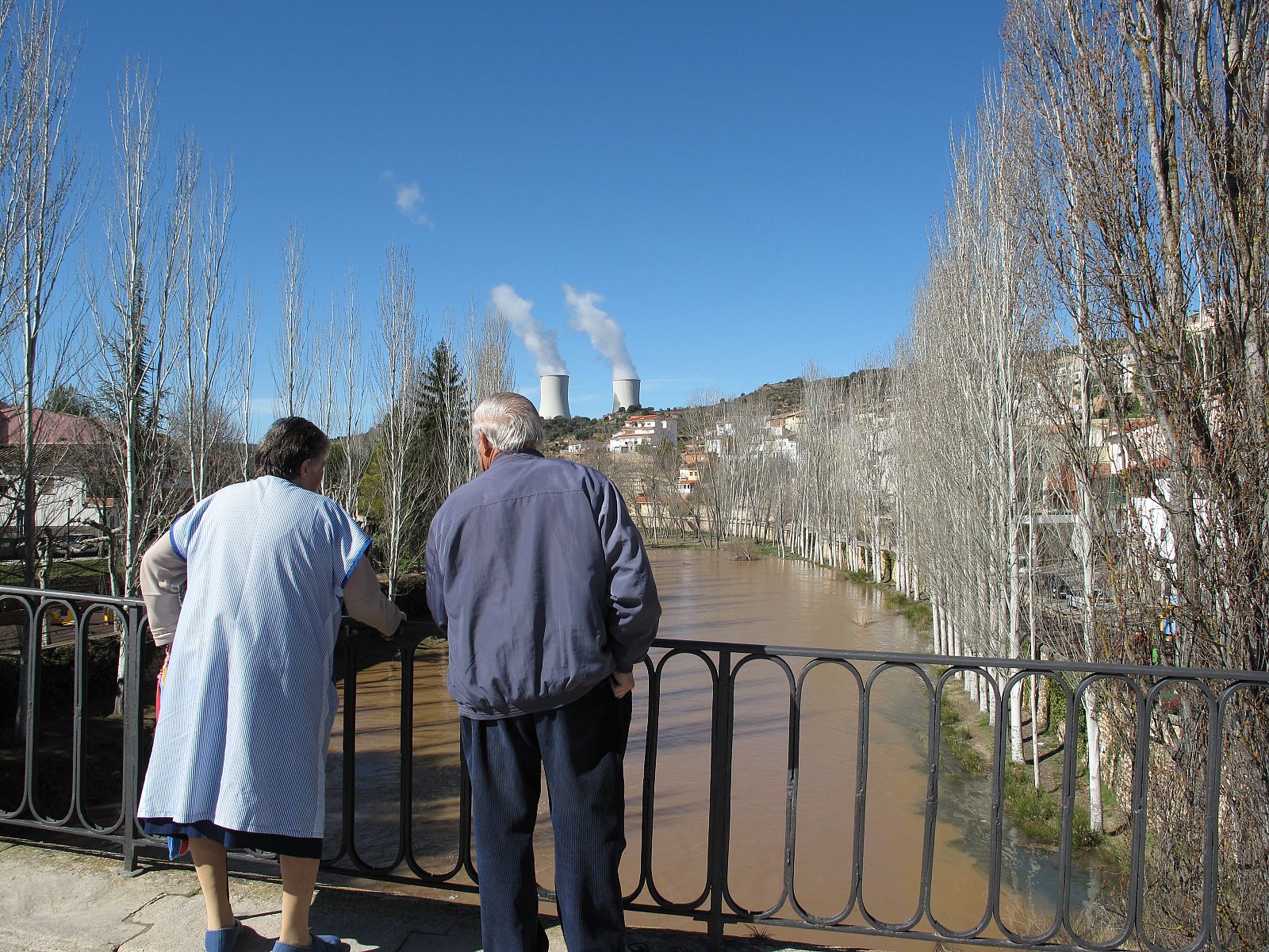 Dos vecinos de Trillo miran el cauce del río Tajo con las torres de la central nuclear al fondo.