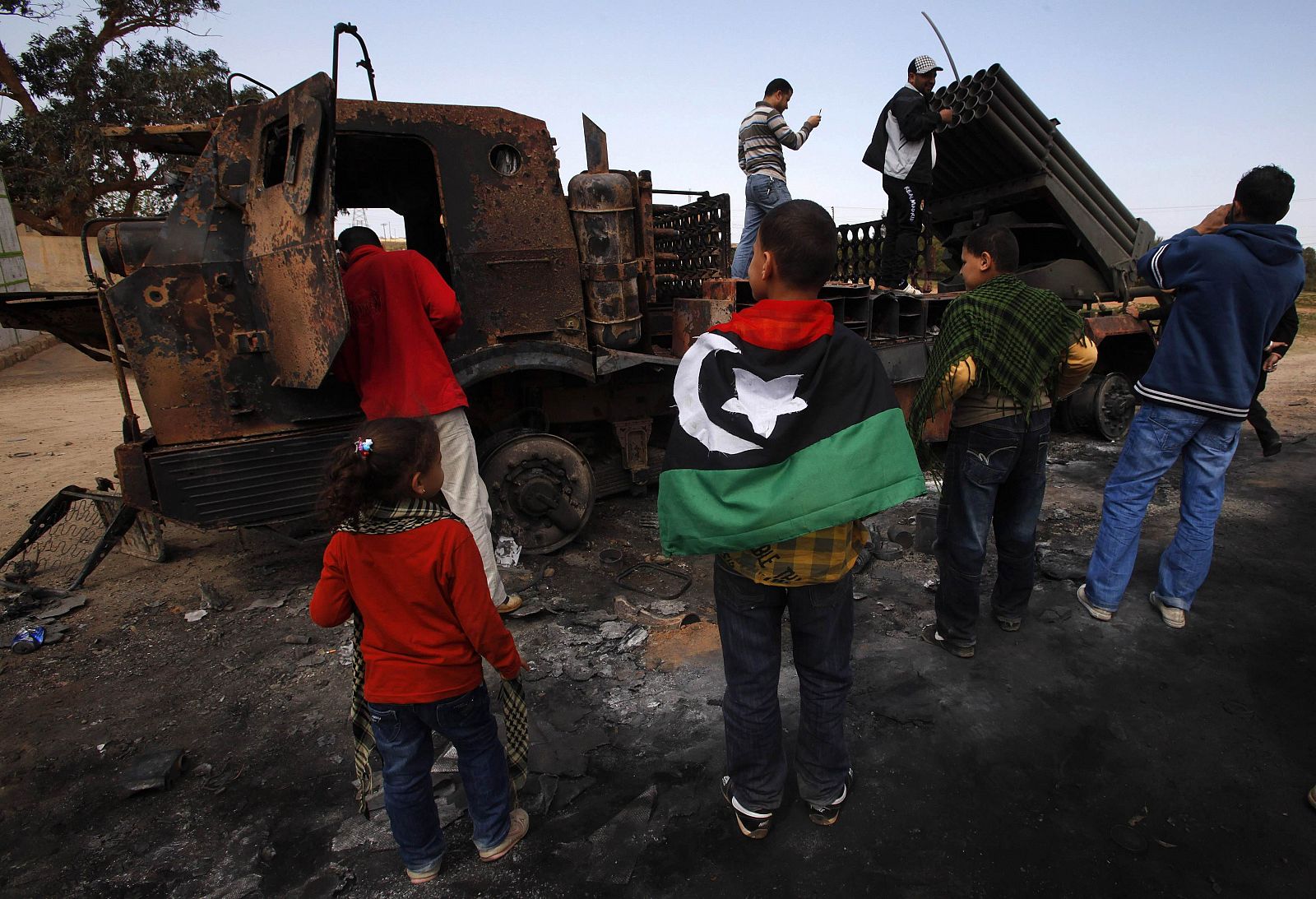 Un grupo de personas mira los restos de armas pertenecientes a las fuerzas de Gadafi y bombardeadas entre Bengasi y Ajdabiya