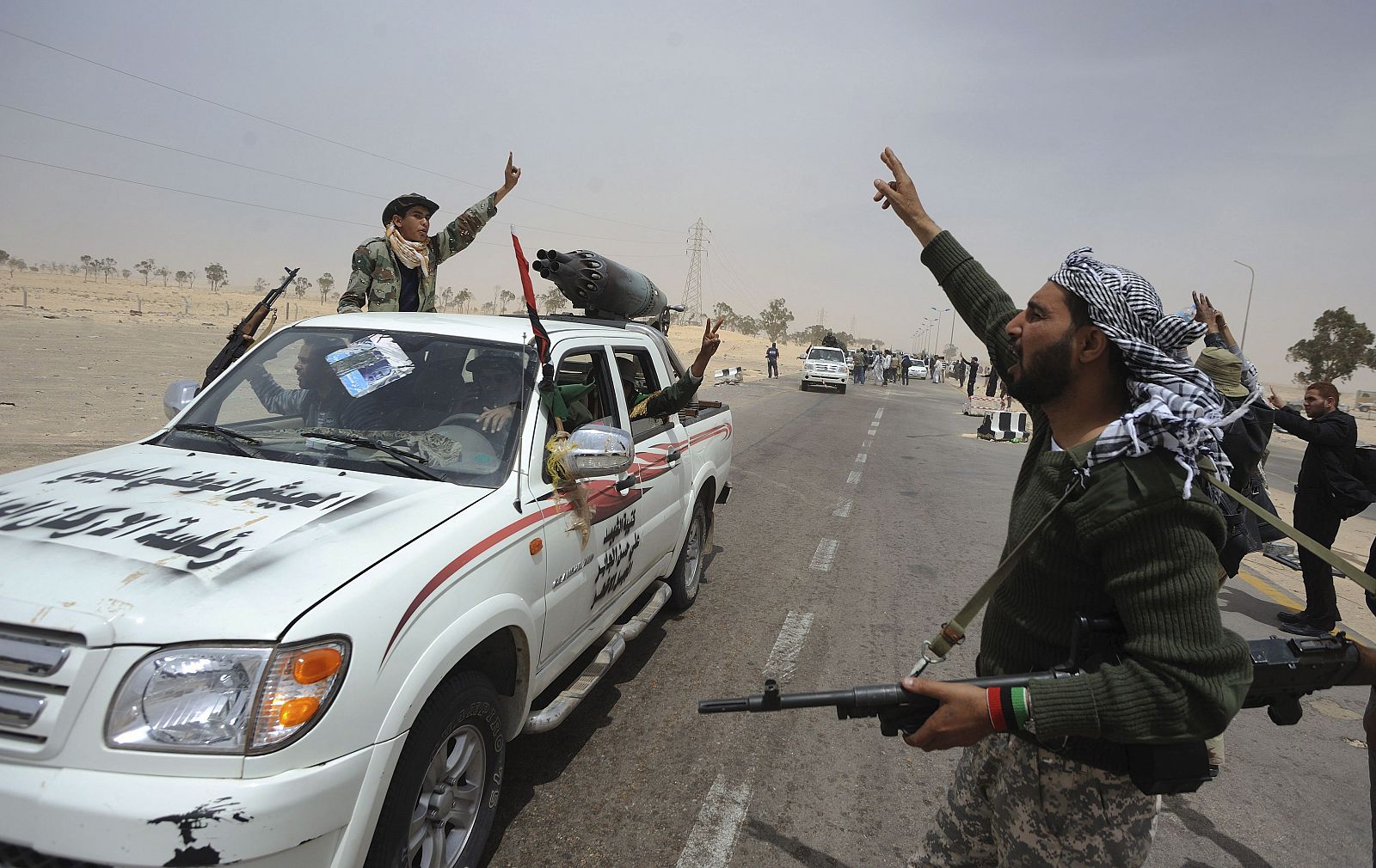Rebeldes libios se saludan a la entrada en Ajdabiya (Libia) poco antes de enfrentarse a las tropas de Gadafi