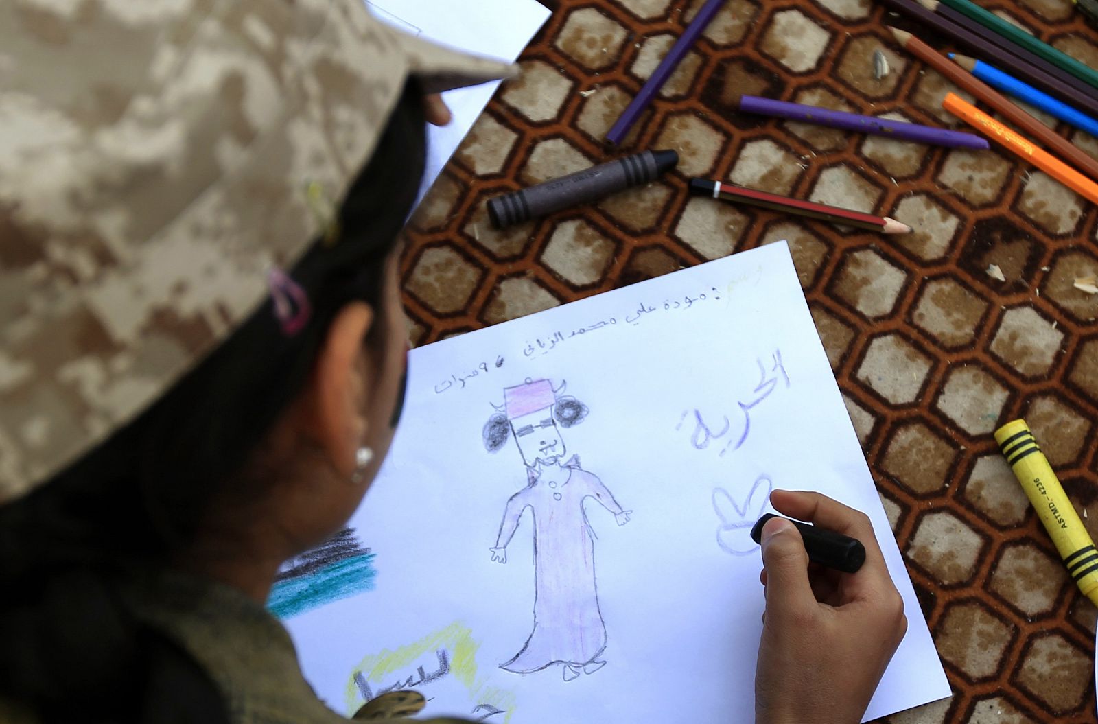 Una niña libia dibuja una caricatura de Gadafi junto con la palabra "Libertad", en Bengazi
