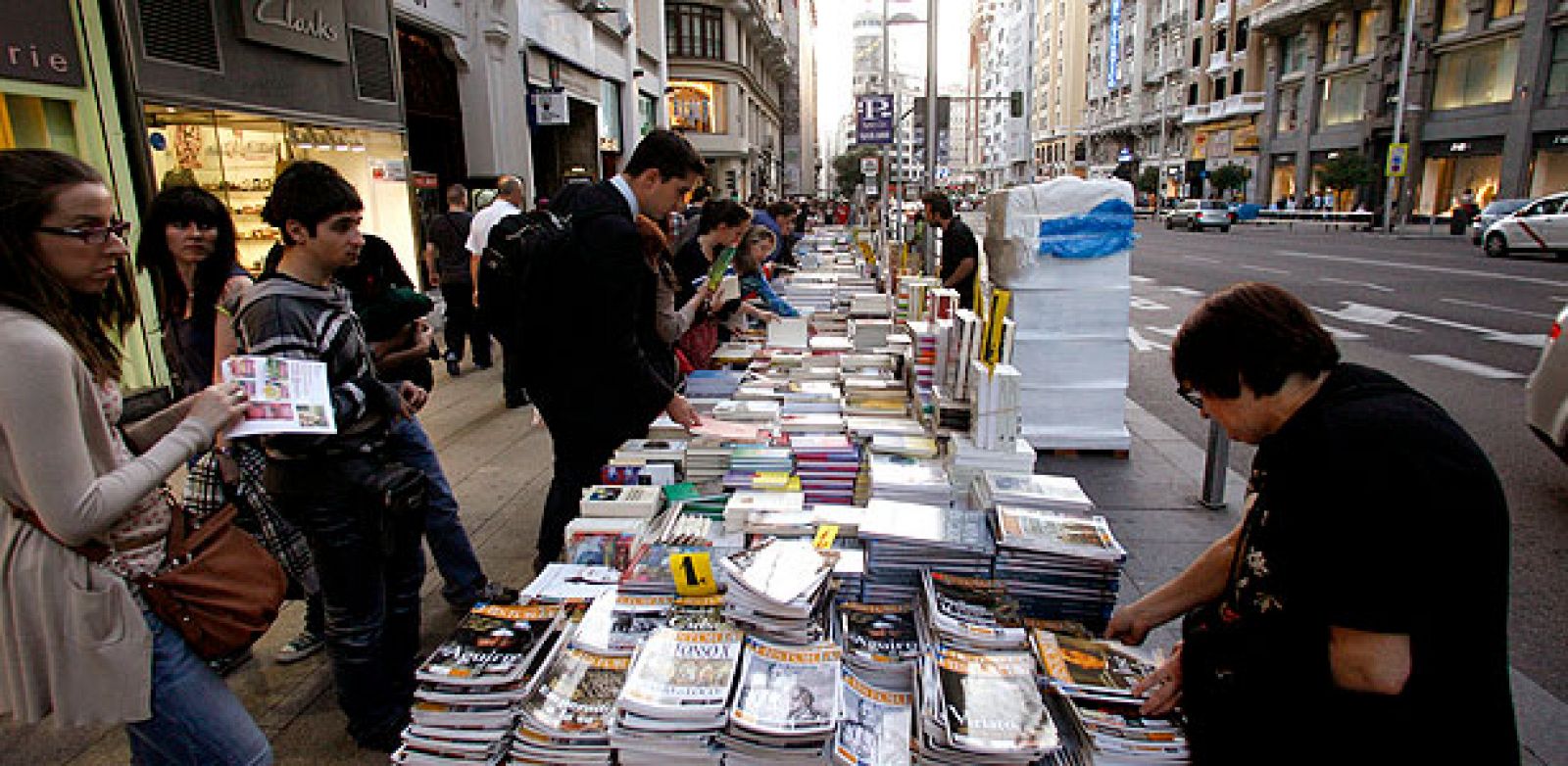 Varias personas observan los libros puestos a la venta en la calle Gran Vía de Madrid, con motivo de la celebración de La Noche de los Libros.