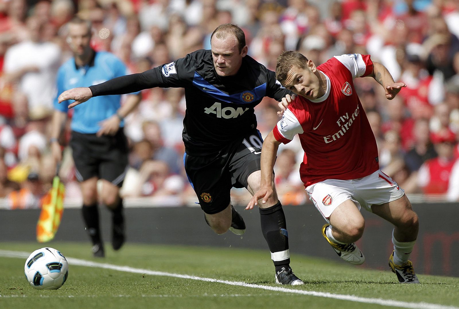 El jugador del Manchester United Wayne Rooney pelea por el control del balón con el jugador del Arsenal, Jack Wilshere.