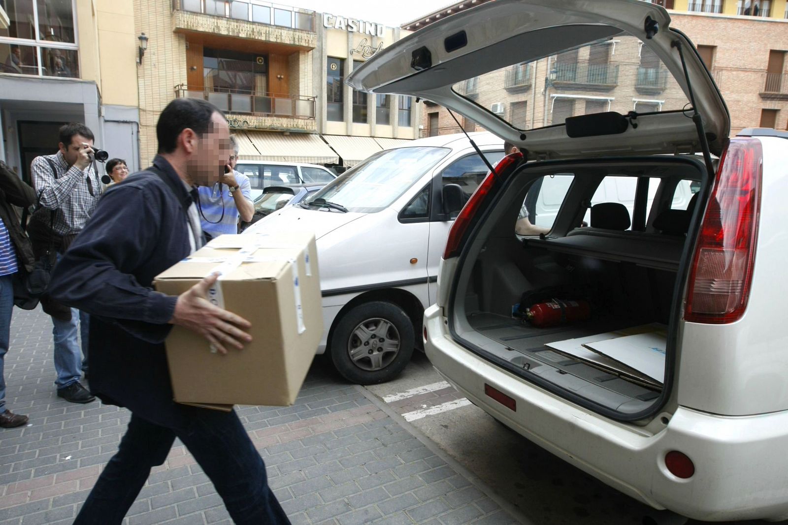 Un miembro de la Brigada de Blanqueo de Capitales de la Policía Nacional introduce en un coche una caja con documentación del Ayuntamiento de Mallén