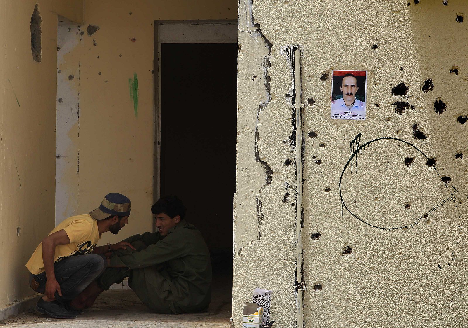 Rebeldes libios en un edificio de Ajdabiya, el día 3 de mayo. En la pared, la fotografía de un civil desaparecido