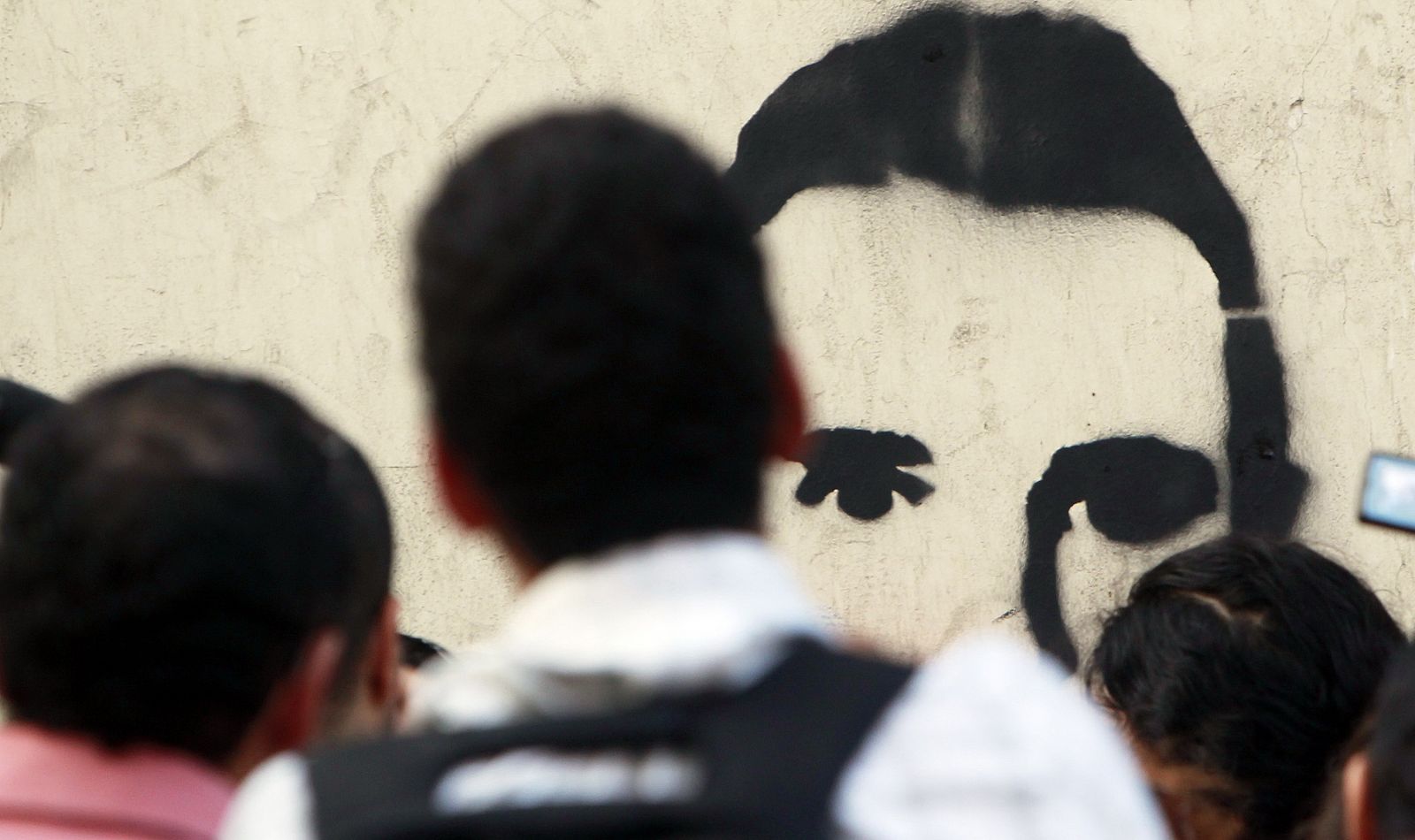 Manifestantes de El Cairo miran un graffiti con el retrato de Jaled Said, muerto hace un año a manos de la policía