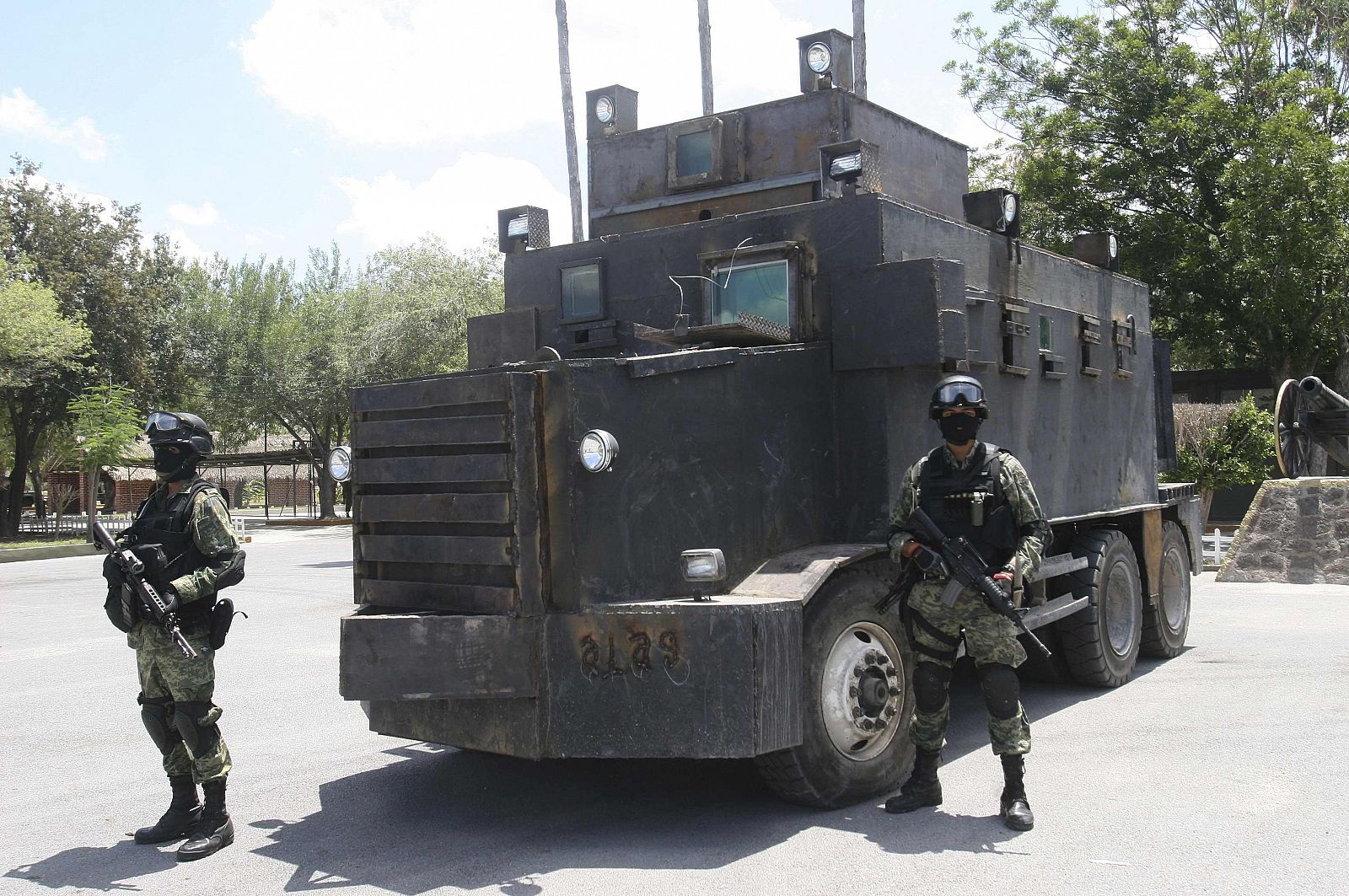 Soldiers stand guard in front of a modified and armored truck as it is displayed to the media at a military base in Reynosa