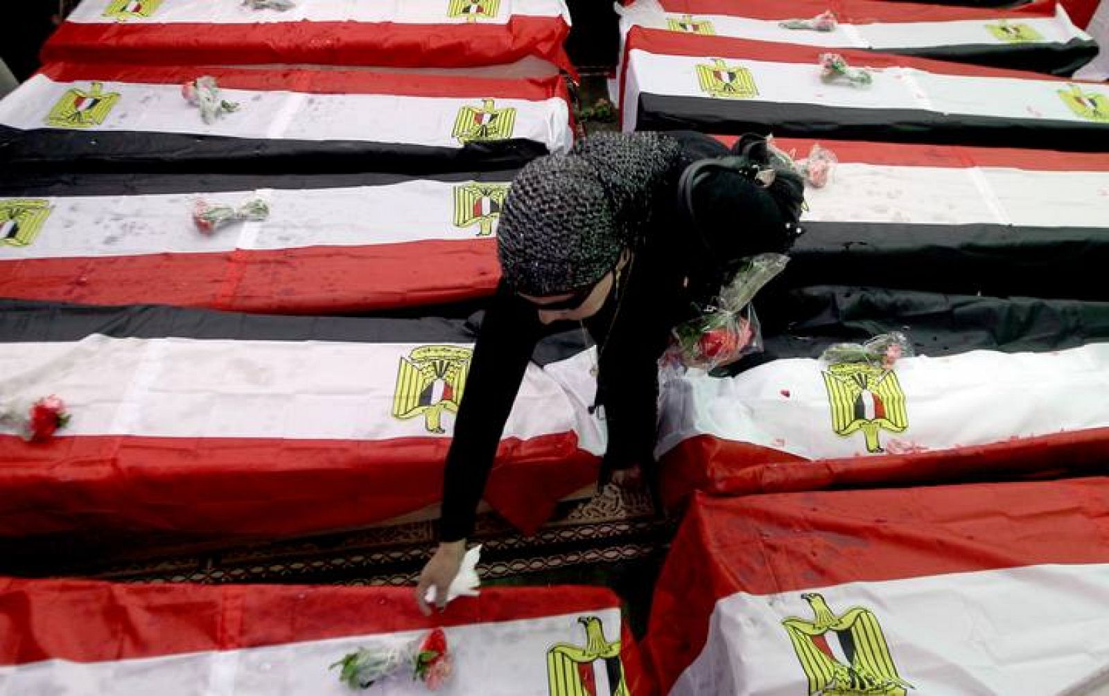 Una mujer deposita una flor durante el funeral de 19 personas muertas en Egipto durante las protestas