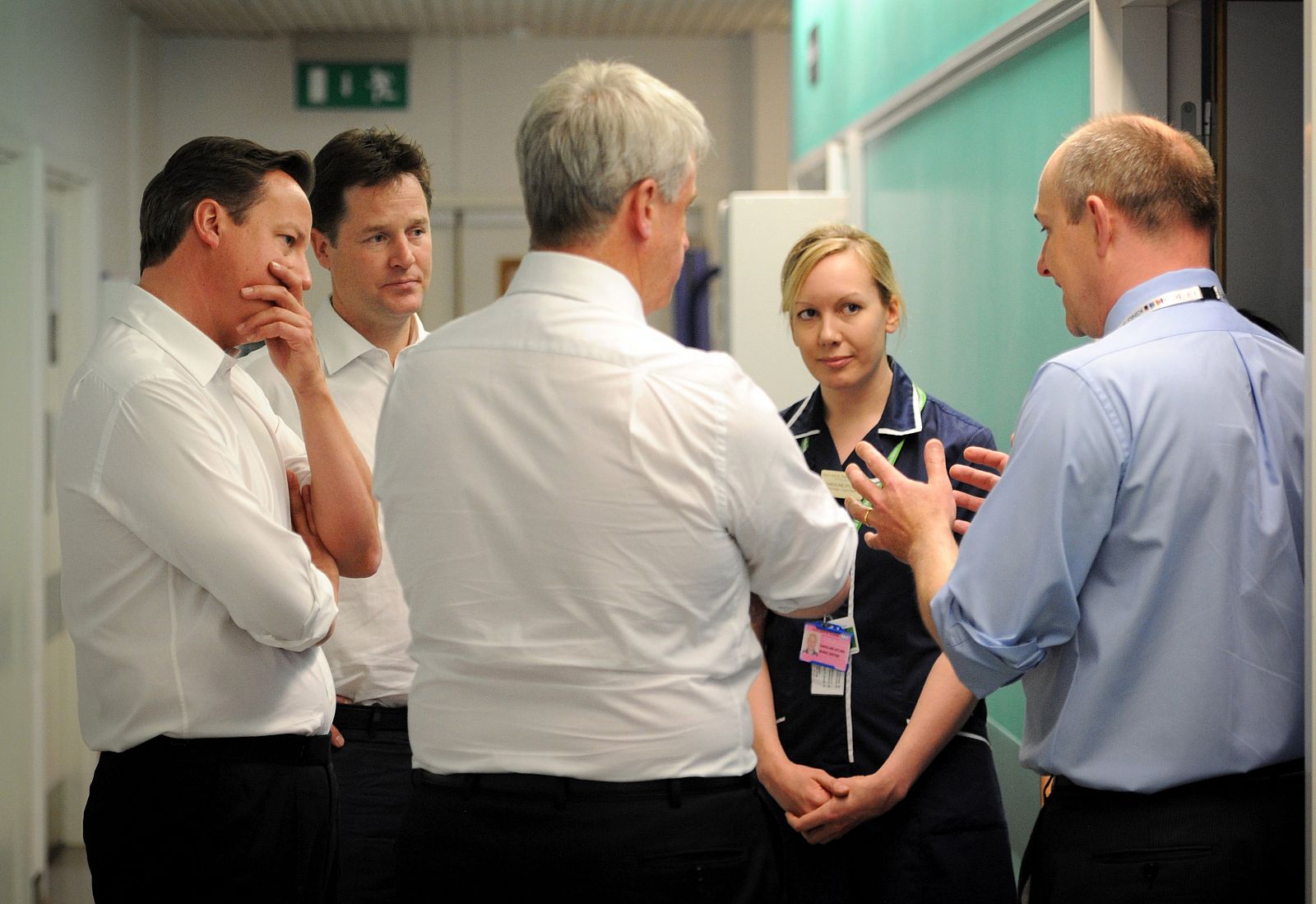 El primer ministro británico, junto a su ministro de Sanidad y el viceprimer ministro escuchan a un doctor y una enfermera.