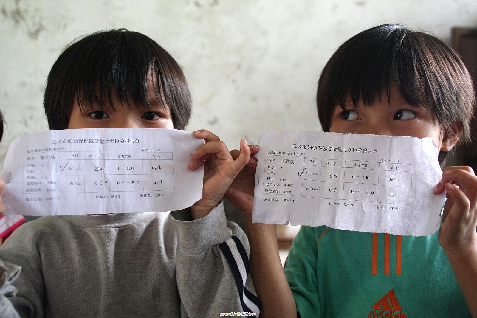 Dos niños muestran el test médico que indica los niveles de plomo