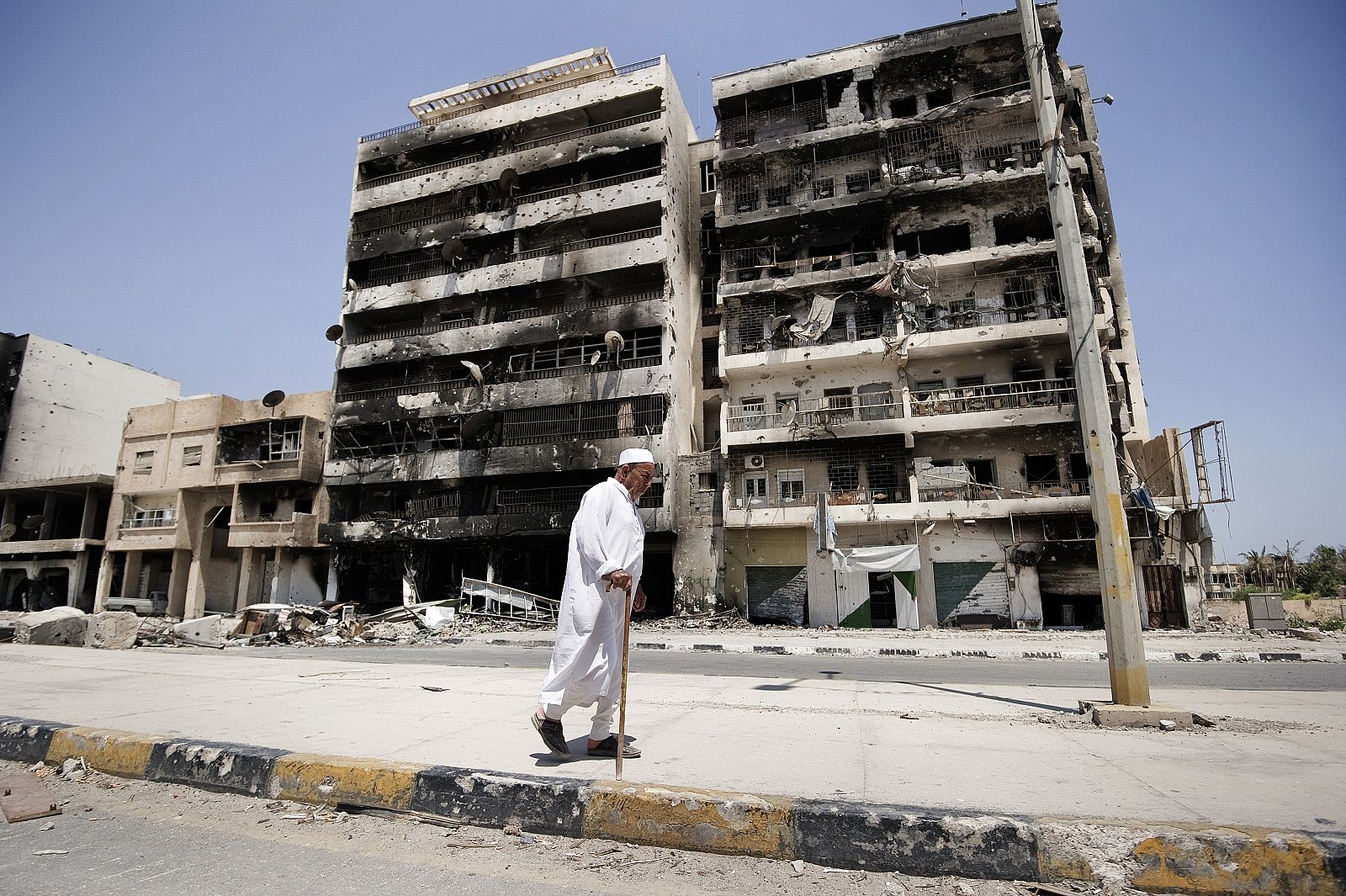 Un hombre pasa junto a un edificio dañado en los bombardeos de la ciudad de Misrata, en Libia