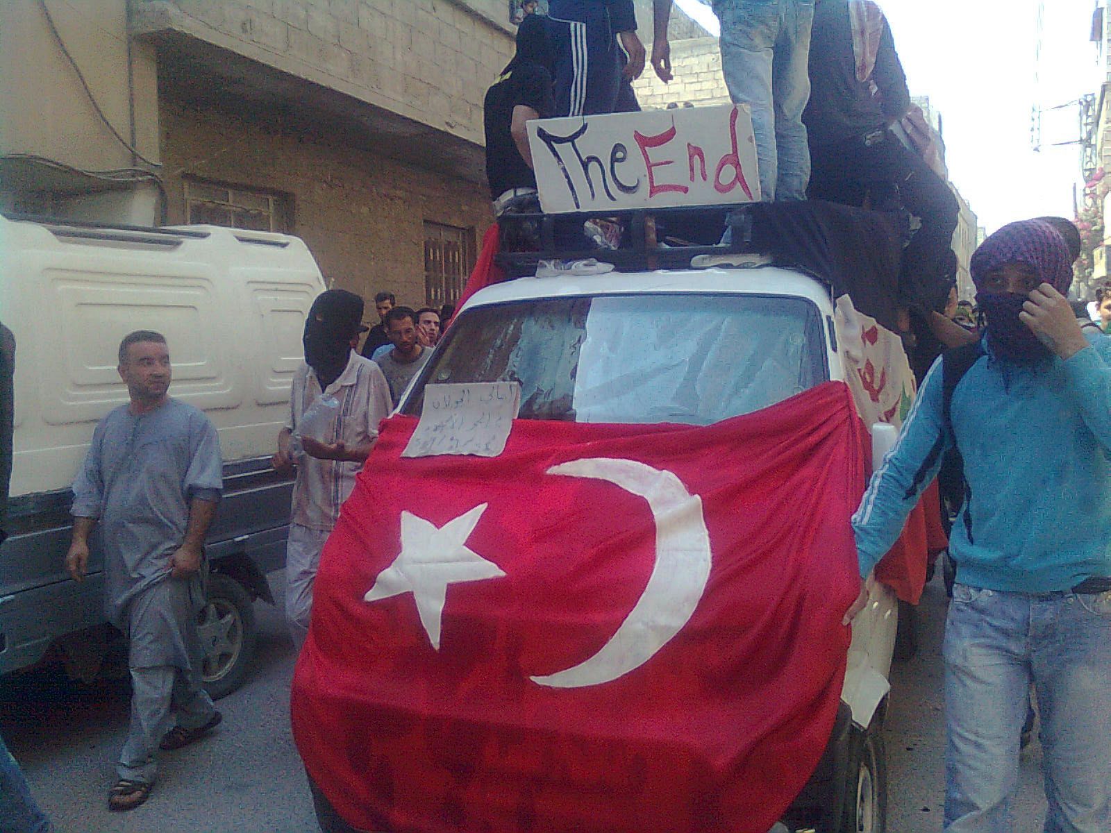 Los manifestantes exhiben una bandera turca y un cartel que anuncia "El final" del régimen sirio en Hajar Al Asswad, Damasco