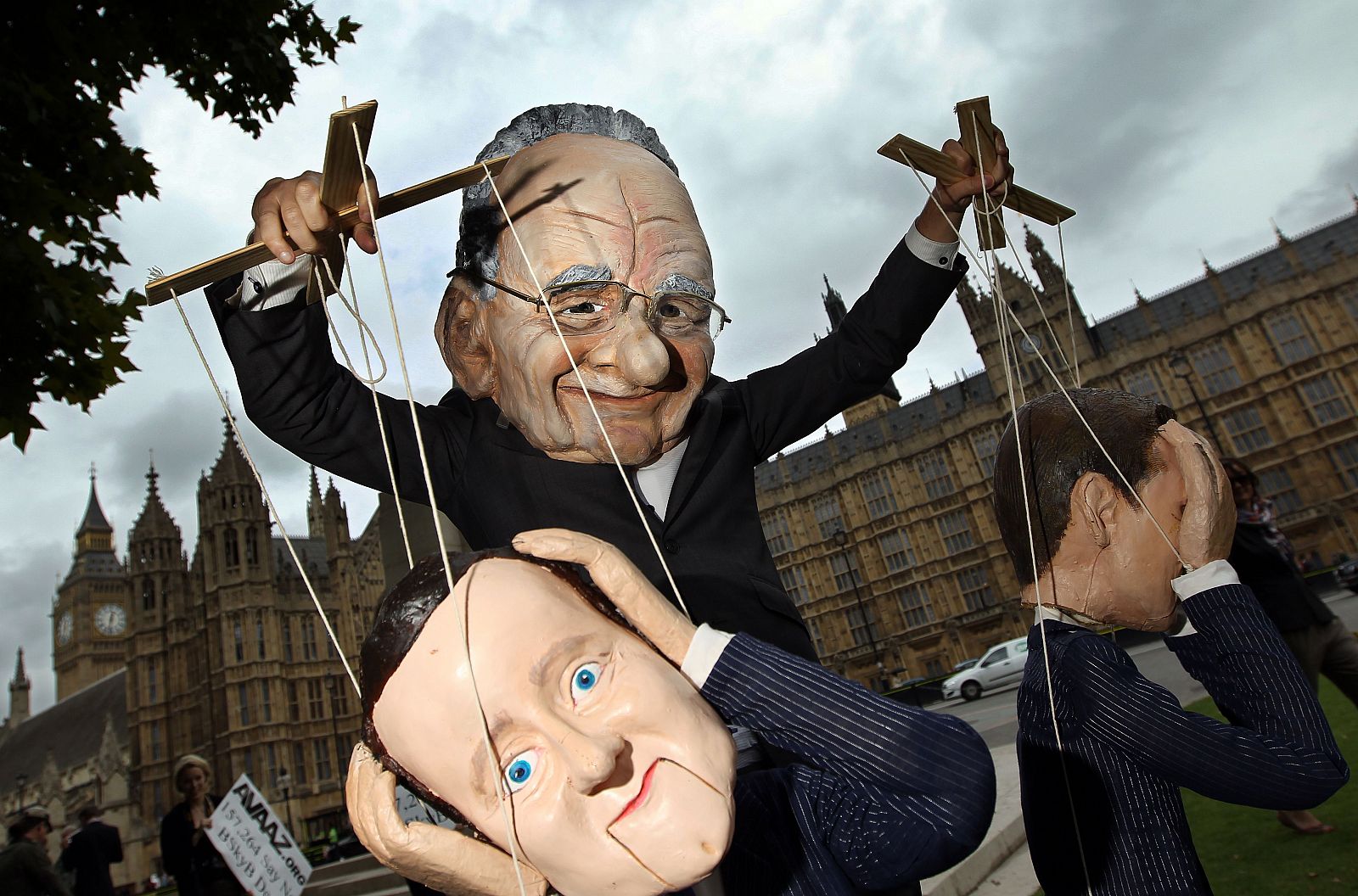Un manifestante disfrazado de Rupert Murdoch maneja una marioneta con el rostro de David Cameron.