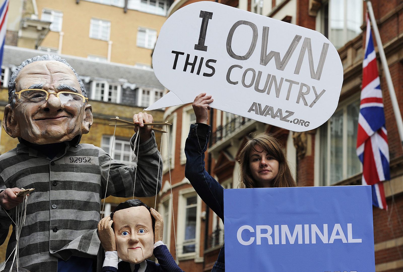 Un manifestante junto con una marioneta de Nick Clegg, lleva una máscara del primer ministro británico, David Cameron, a las afueras del apartamento del jefe ejecutivo de la cadena "News Corporation" en Londres