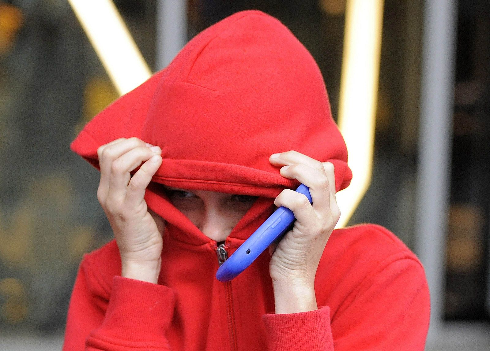 Un menor de doce años trata de cubrirse la cara con su capucha tras salir del tribunal de Manchester, donde admitió un cargo de robo.