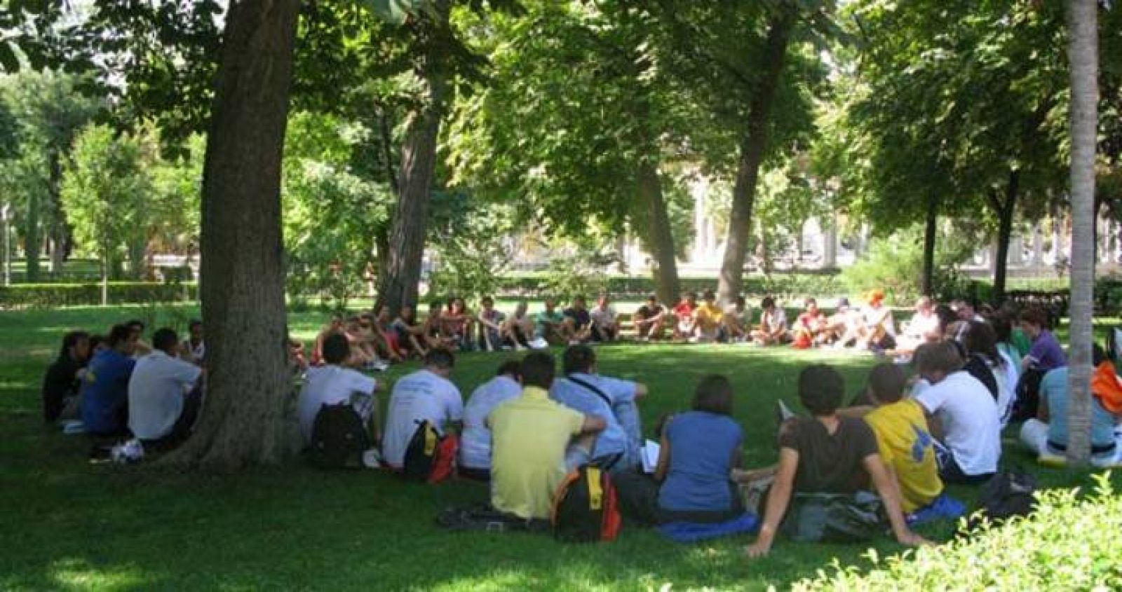 Varios peregrinos concentrados en círculo bajo los árboles del madrileño Parque del Retiro