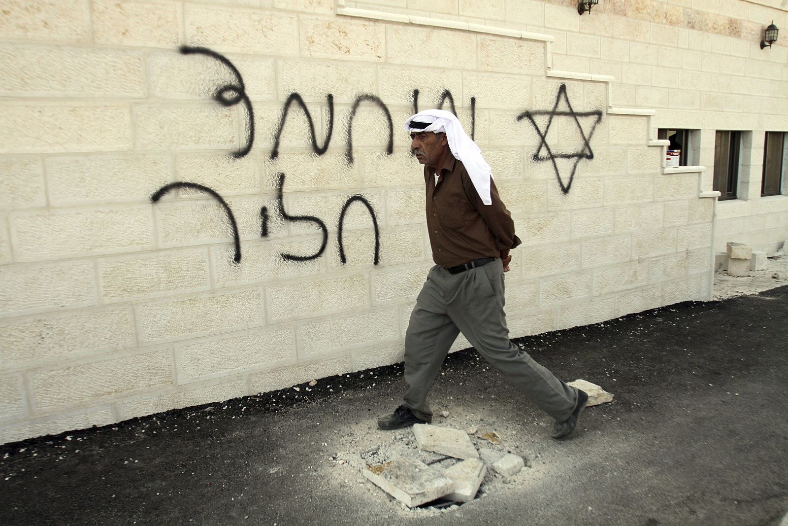 Un hombre pasa frente a una de las pintadas realizadas por colonos israelíes en una mezquita en Cisjordania