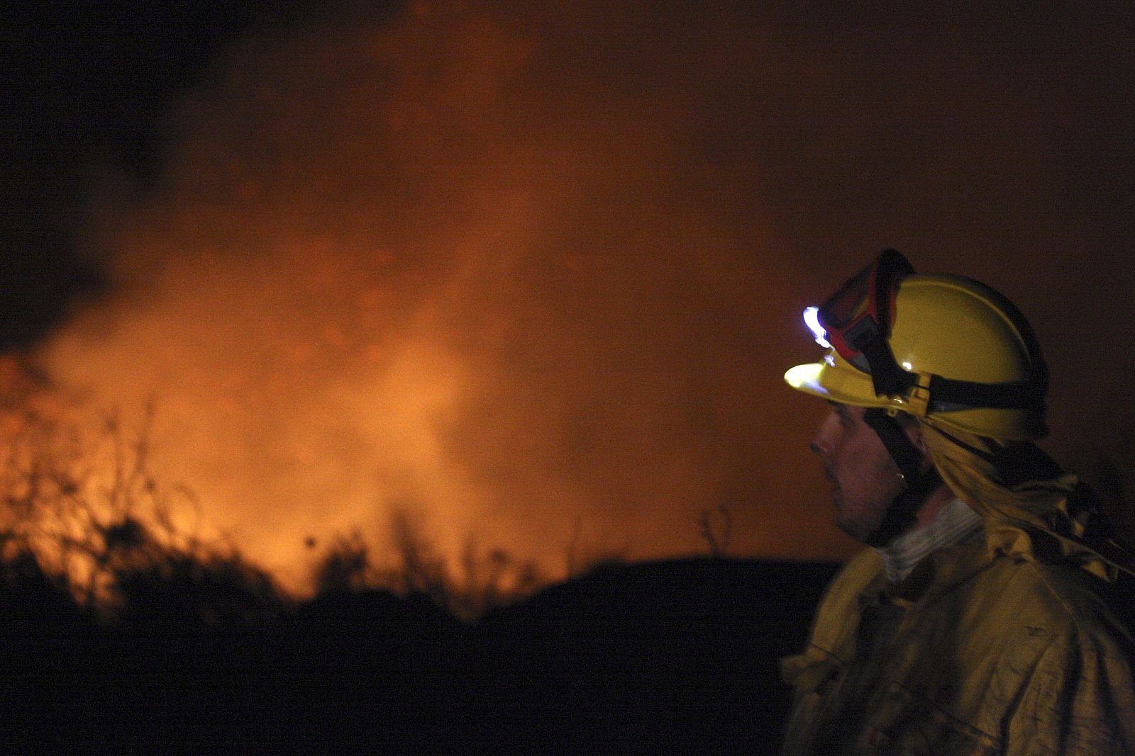 Un bombero observa las llamas del incendio forestal declarado esta noche en el Parque Natural Arribes del Duero, en el término municipal salmantino de La Bouza.
