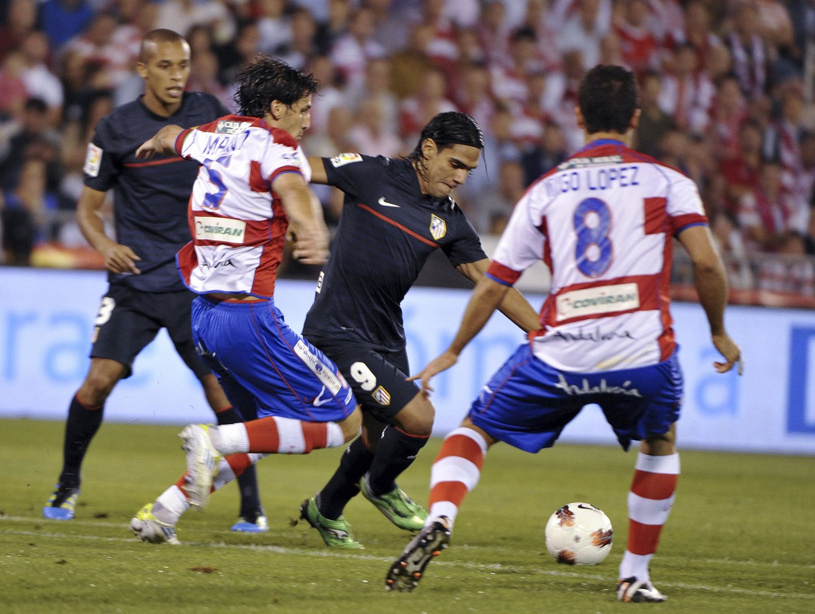 El delantero colombiano del Atlético de Madrid, Radamel Falcao, intenta marcharse de los defensas del Granada CF, Iñigo López y Diego Mainz.