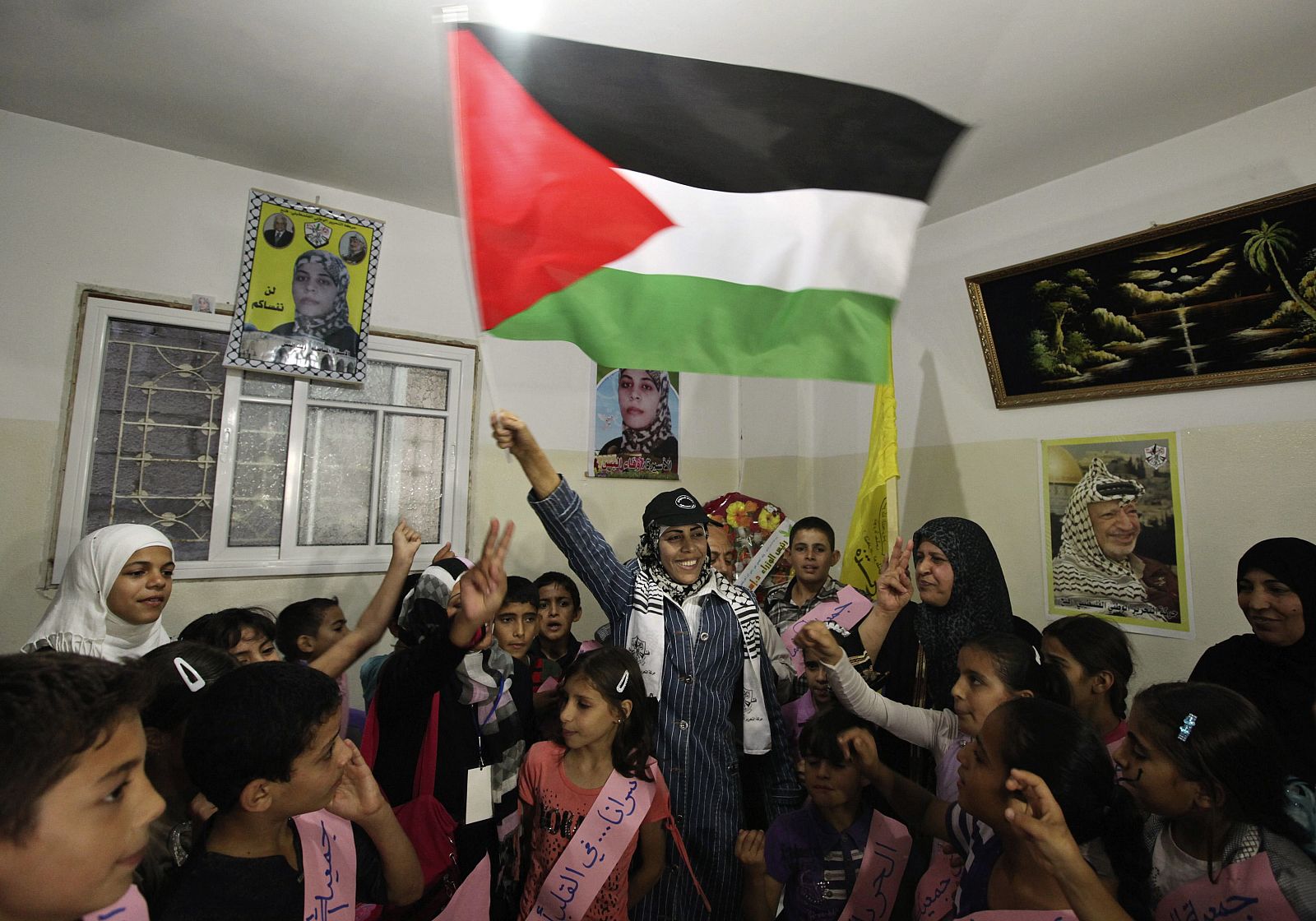 Wafa Al-Biss ondea una bandera palestina en su casa, donde fue recibida por un grupo de niños.