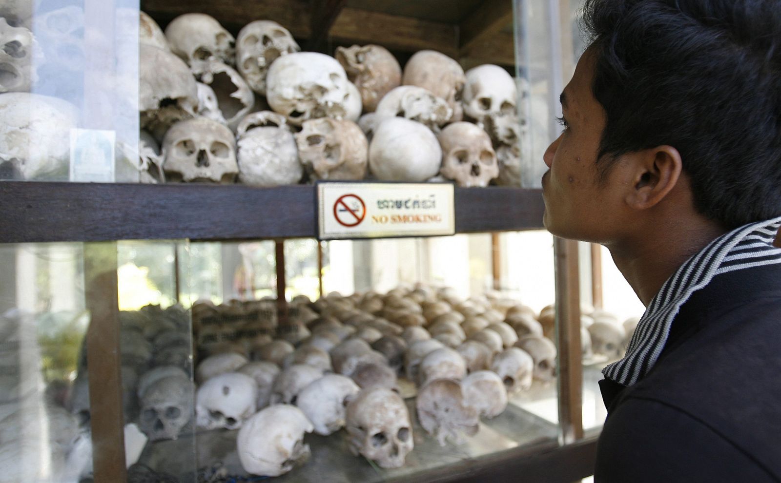 Un hombre observa las calaveras de las víctimas del Jemer Rojo en los campos de exterminio de Choeung Ek, a las afueras de Phnom Penh (Camboya)