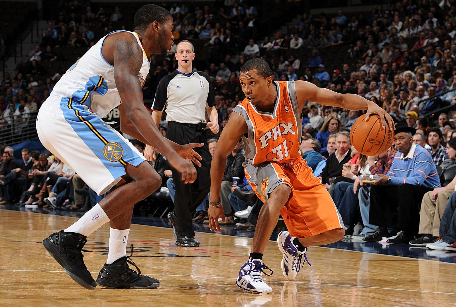 Sebastian Telfair, de los Phoenix Suns, bota el balón ante la presión de un jugador de los Denver Nuggets.