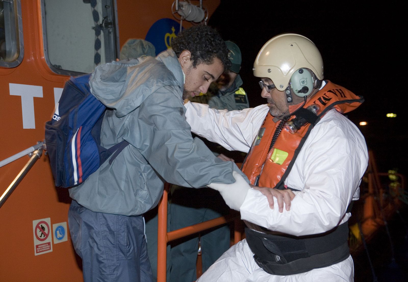 Uno de los 56 inmigrantes magrebíes es ayudado a desembarcar por un miembro de Salvamento Marítimo a su llegada al puerto de Motril.