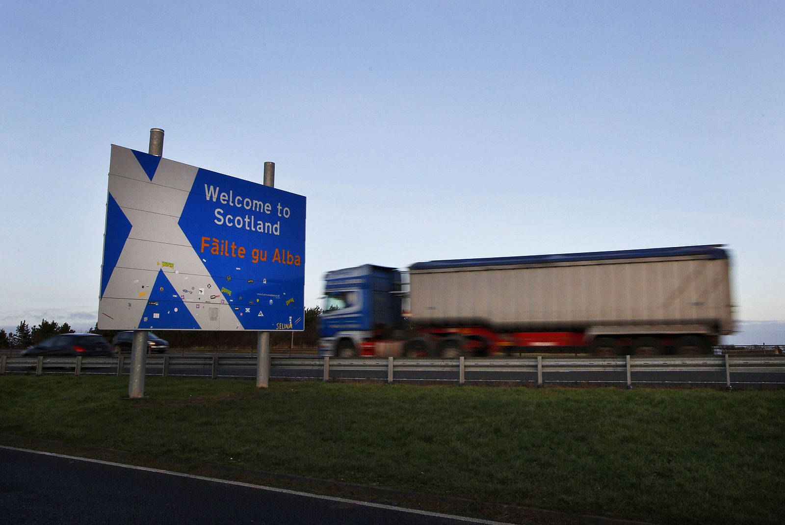 Un camión pasa frente a un cartel de bienvenida a Escocia