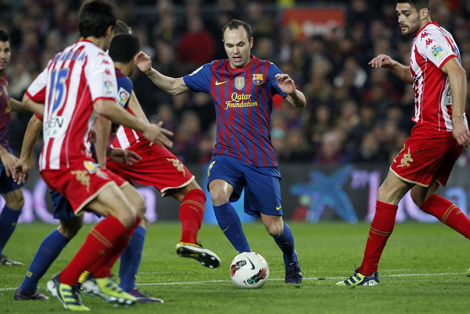 Barcelona's Iniesta is challenged by Sporting de Gijon's players during their Spanish first division soccer match at the Nou Camp stadium in Barcelona