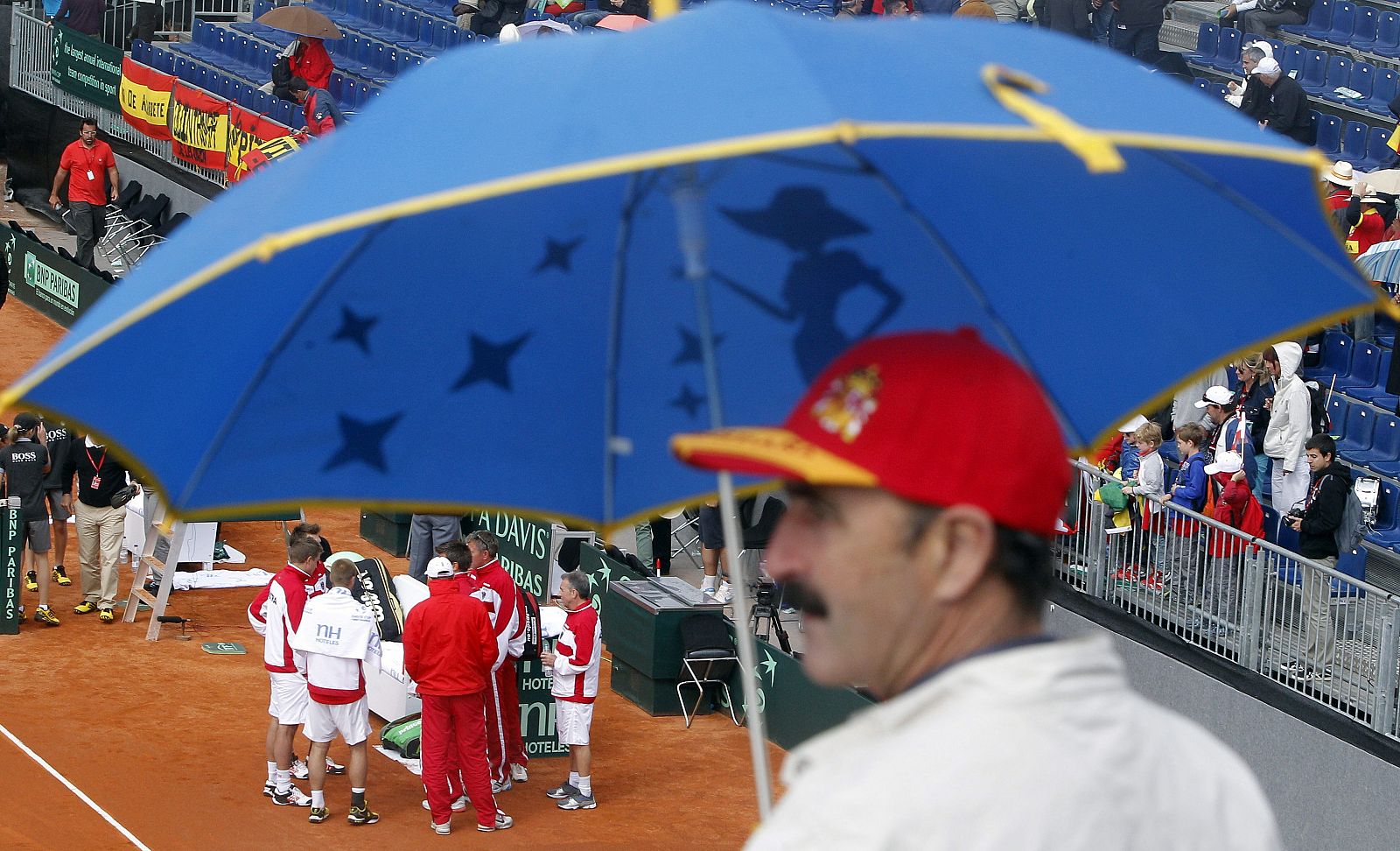 Los tenistas austríacos esperan a que amaine la lluvia durante el partido de dobles.