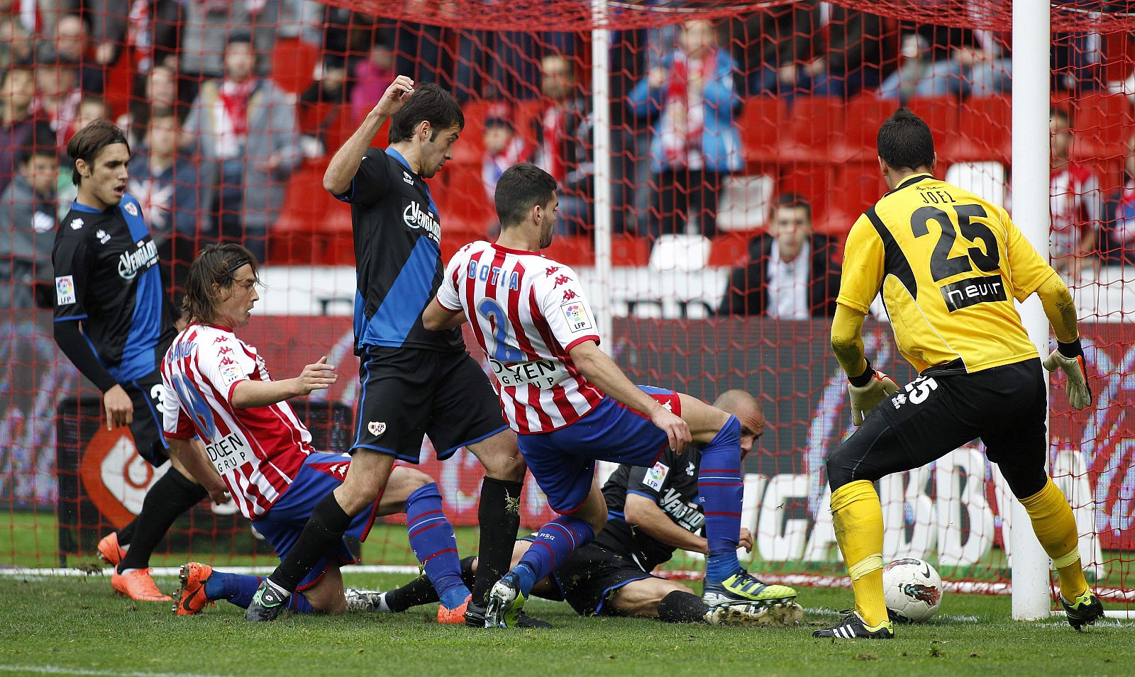 El delantero argentino del Sporting de Gijón, Gastón Sangoy (2i) bate al portero del Rayo Vallecano, Joel Robles (d)