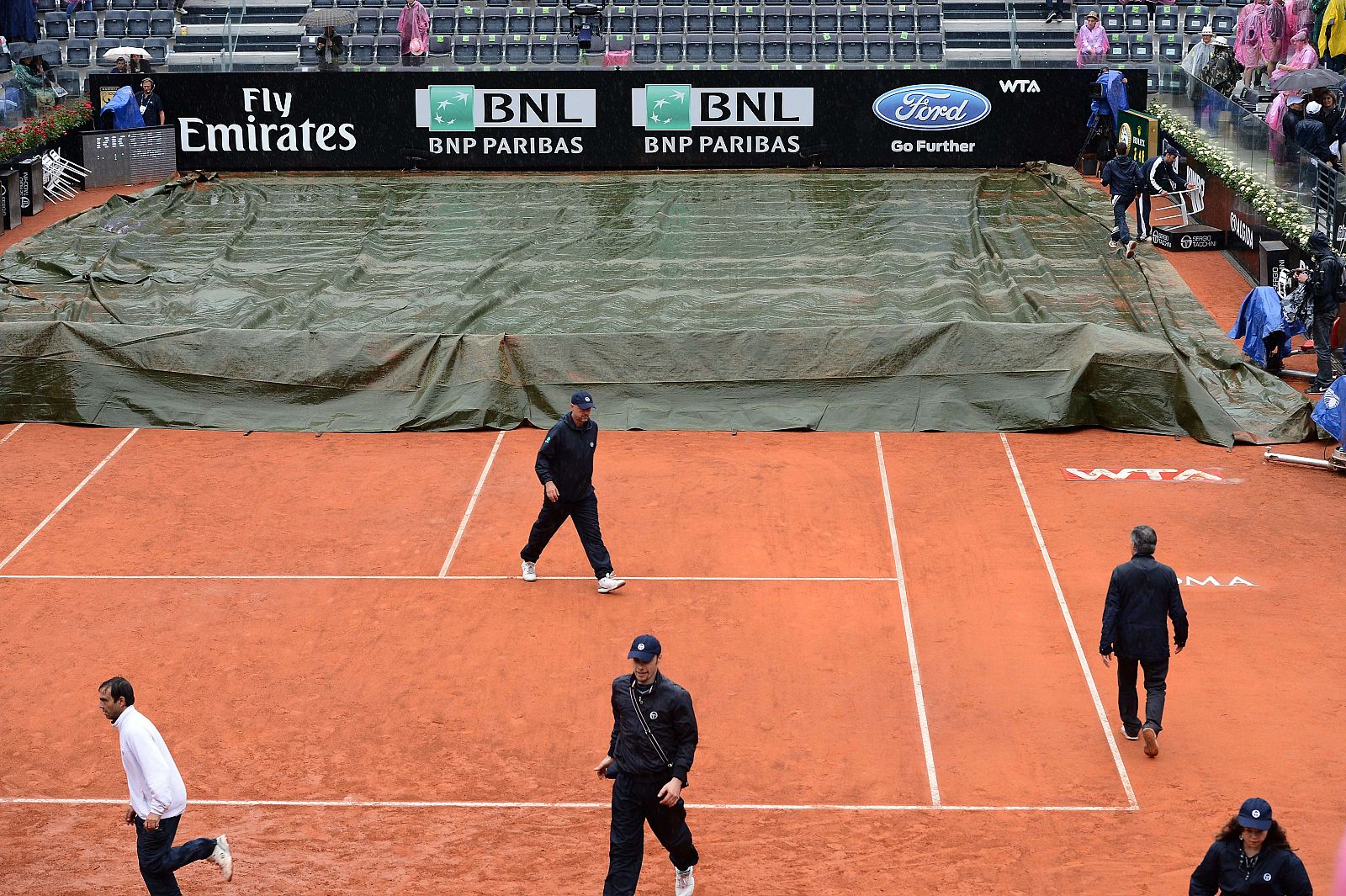 Los operarios del Masters 1000 de Roma tapan la pista con una lona por la lluvia.