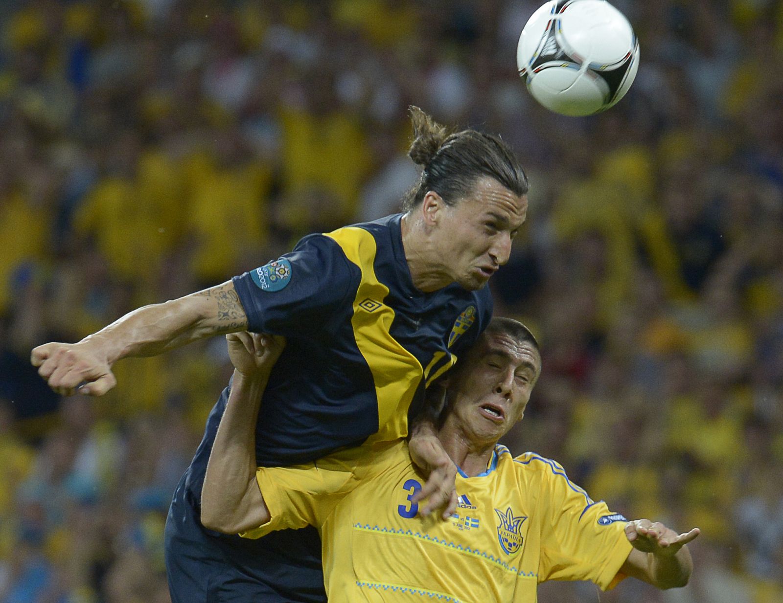 Zlatan Ibrahimovic remata ante el defensa ucraniano Yevhen Khacheridi en el primer partido de la Euro 2012.