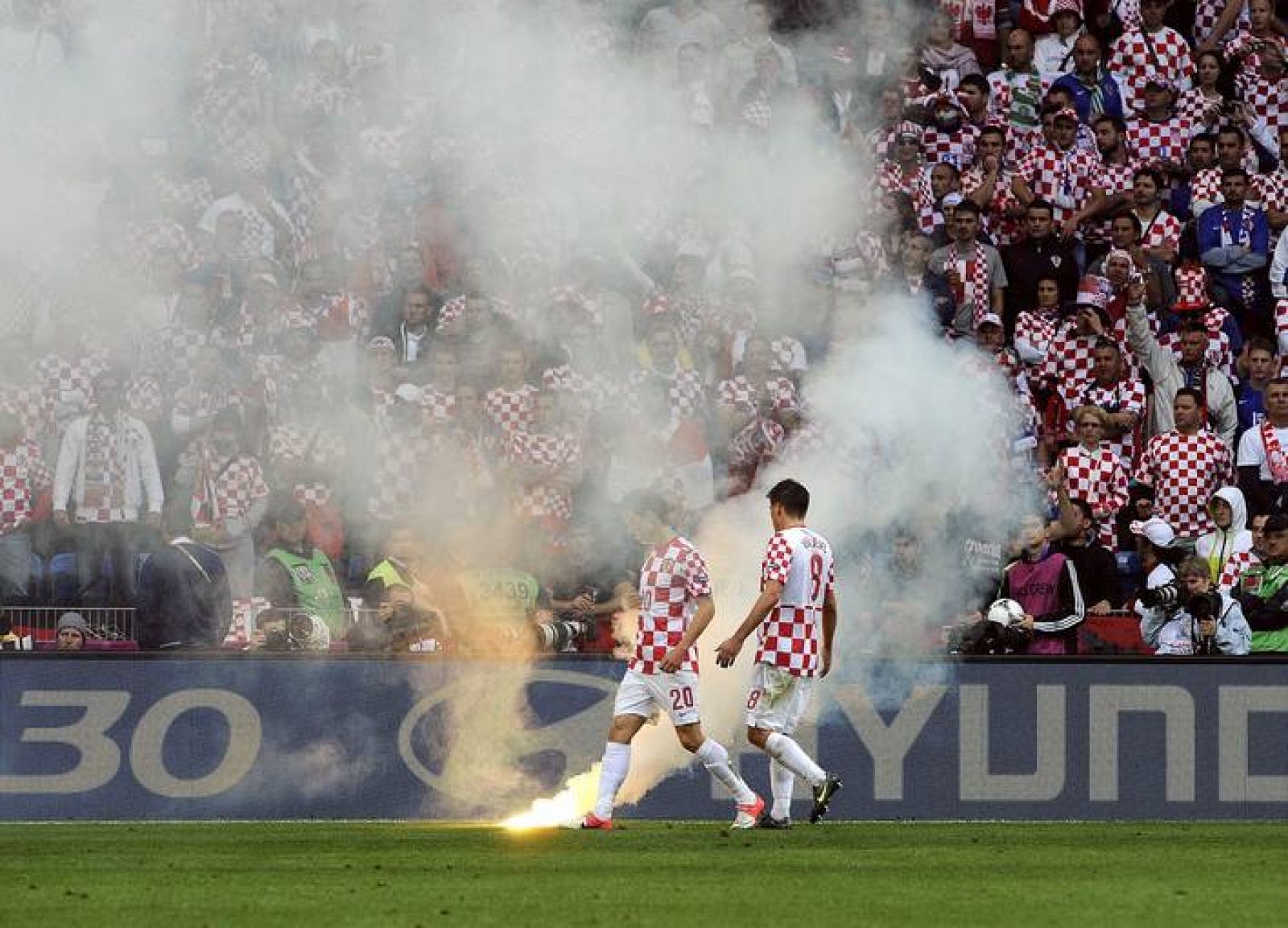 Dos jugadores croatas observan una bengala lanzada al terreno de juego