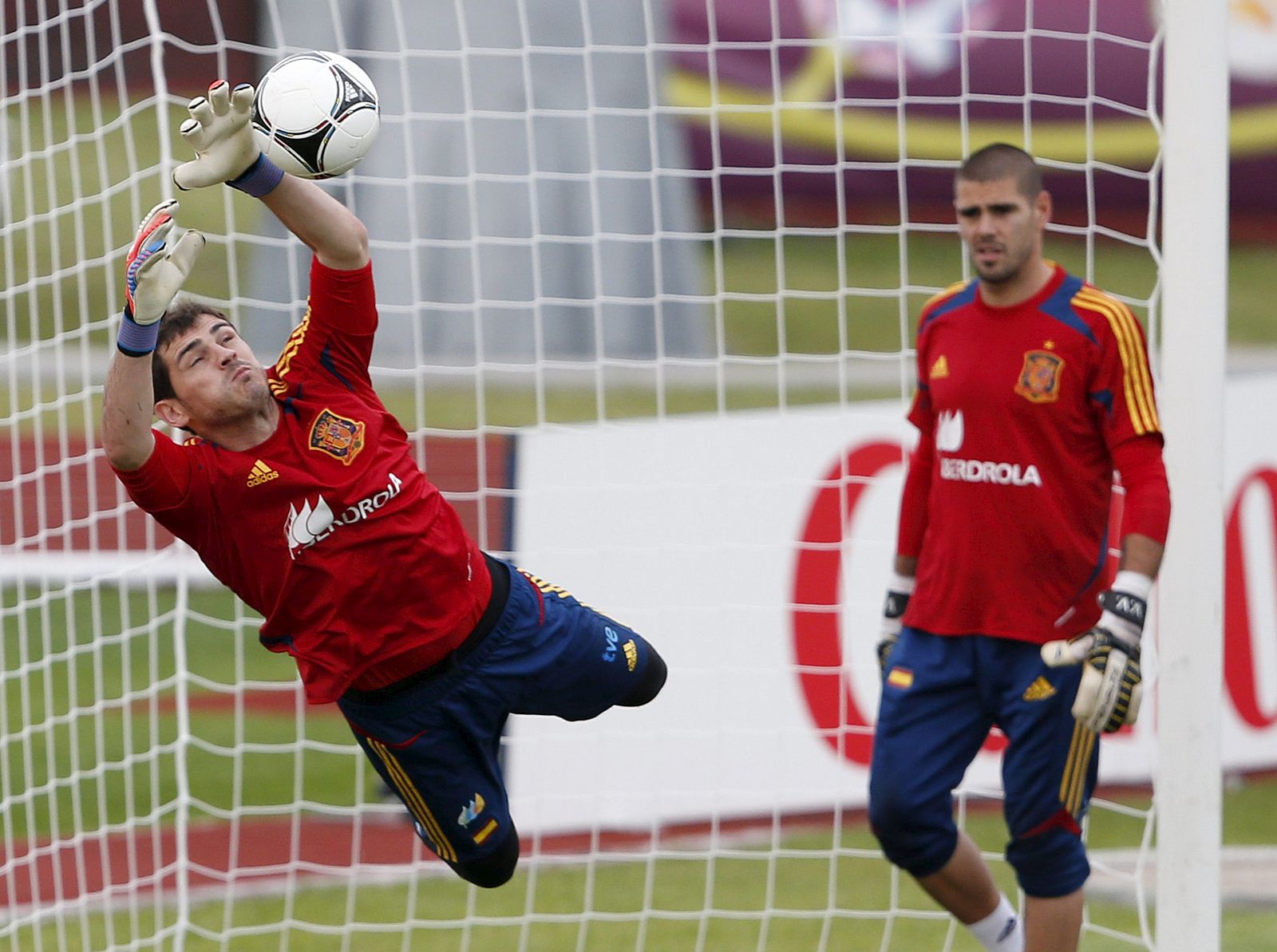 El guardameta español Iker Casillas (izda) detiene un balón junto a su compañero Víctor Valdés.