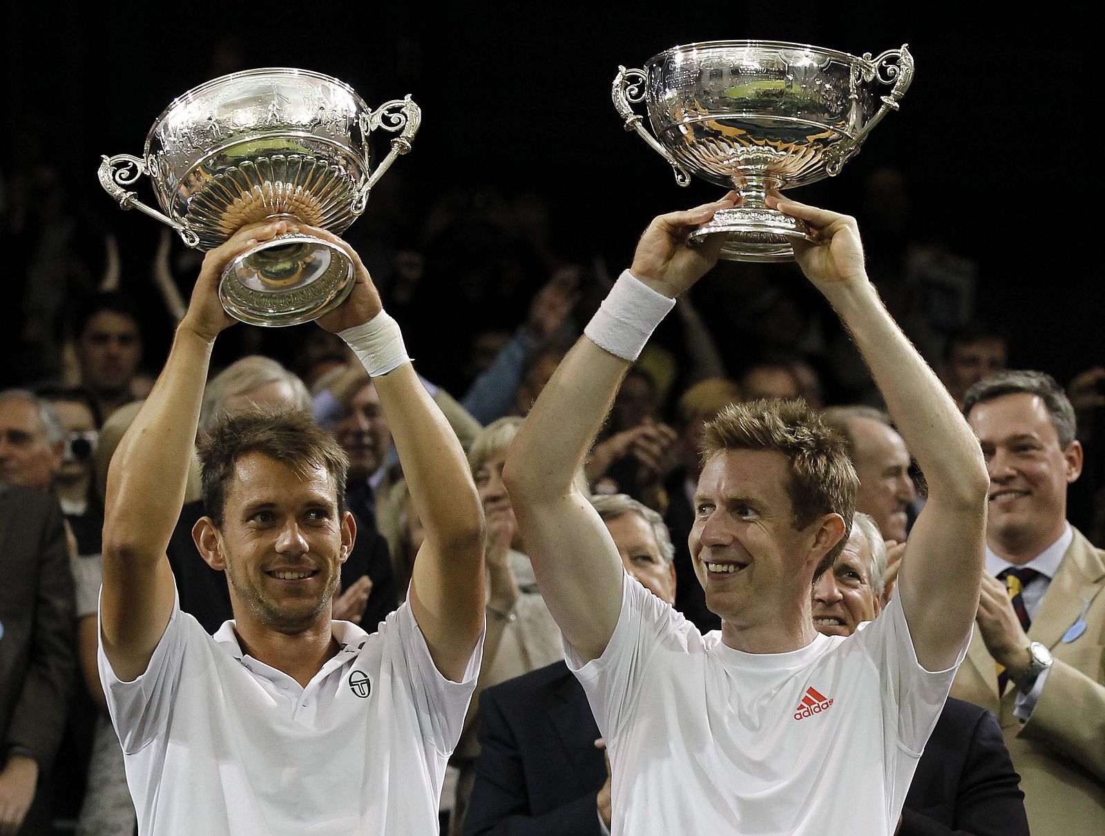 Los tenistas Jonathan Marray de R. Unido (d) y Frederik Nielsen de Dinamarca alzan sus trofeos tras ganar la final de dobles masculina ante Robert Lindstedt de Suecia y Horia Tecau de Rumania, en el Abierto de tenis de Wimbledon.