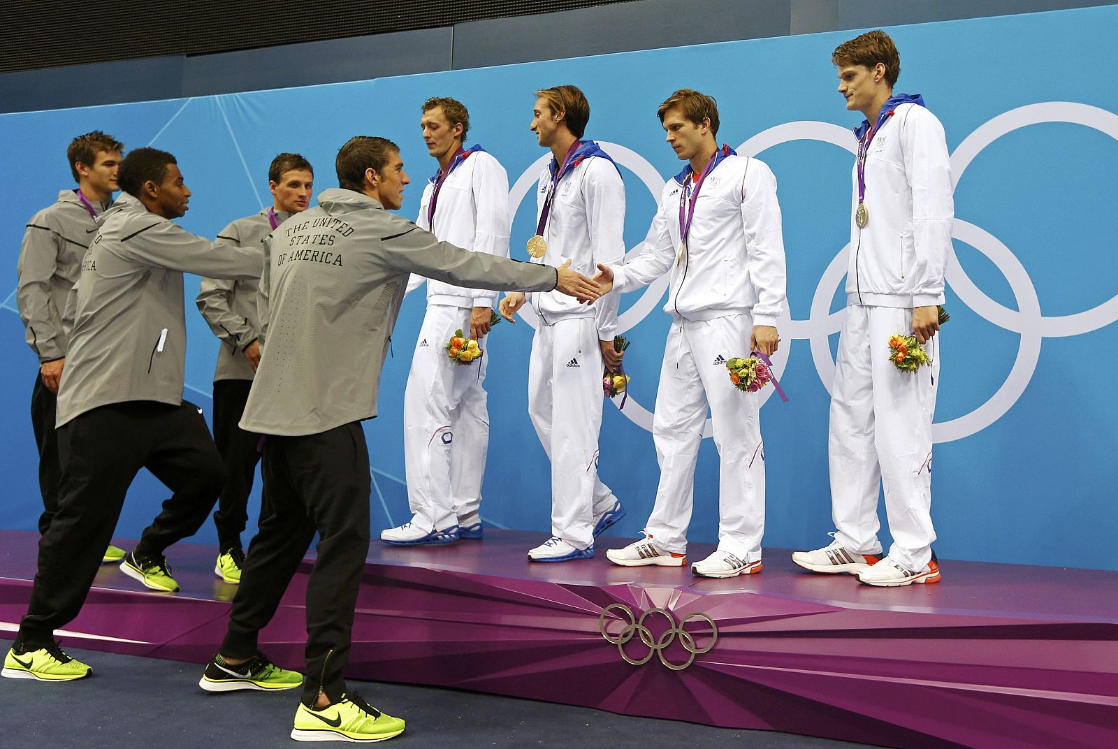 El equipo de USA saluda al de Francia después de que estos se llevaran el oro en el 4x100m.