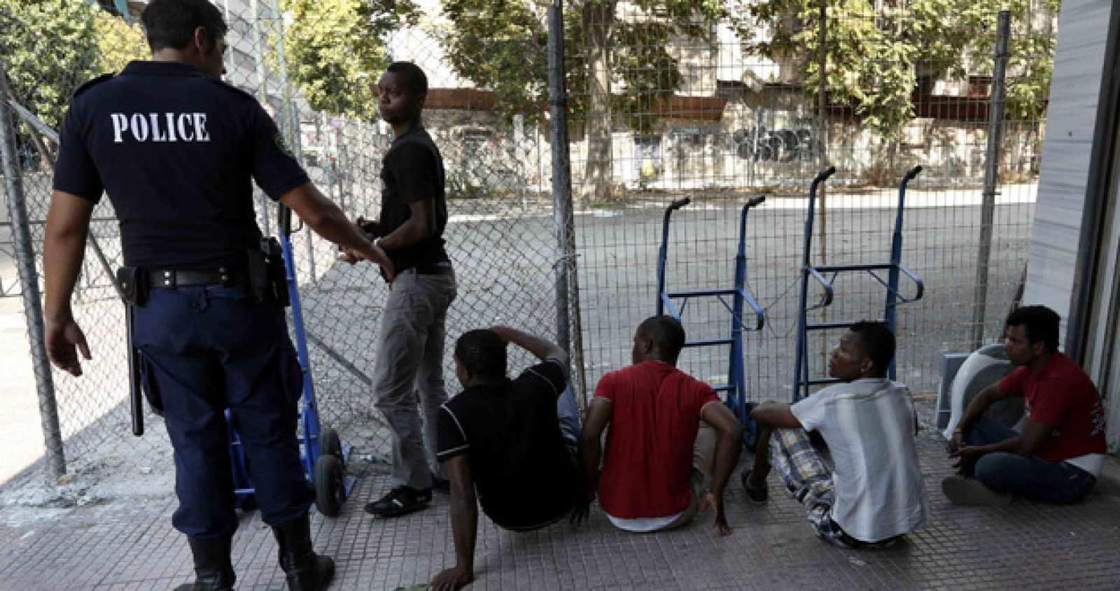Un policía con un grupo de inmigrantes para comprobar sus documentos de identificación en una de las redadas policiales contra la inmigración ilegal en Atenas el 14 de agosto.