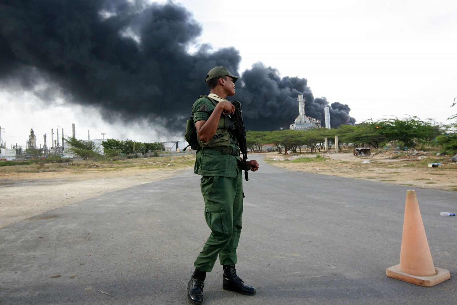 Un soldado monta guardia frente a la refinería de Amuay, cuyos tanques están ardiendo, el 28 de agosto