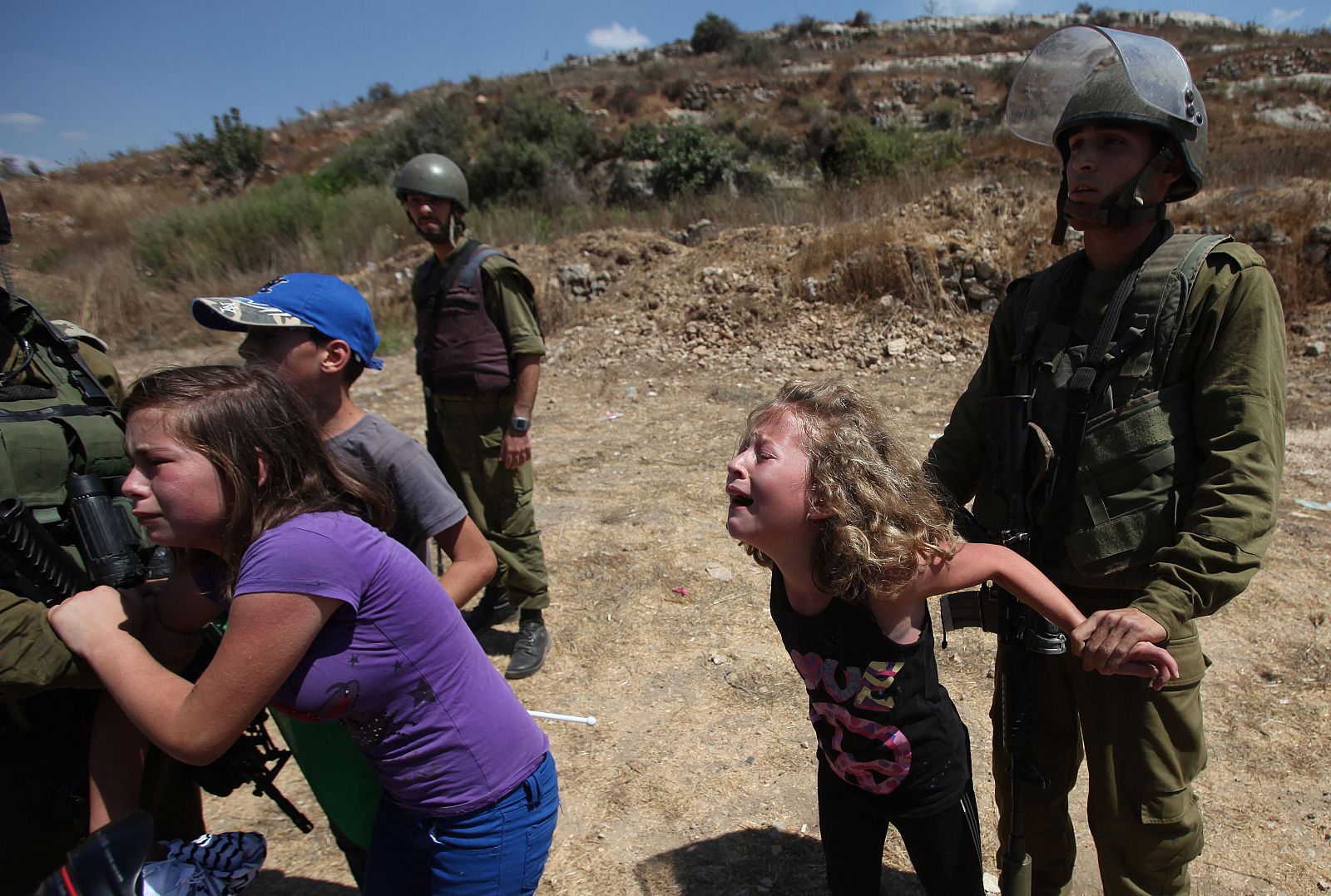 Soldados israelíes retienen a dos niñas palestinas mientras su madre es arrestada durante una manifestación en Nabi Saleh, Cisjordania, el 24 de agosto