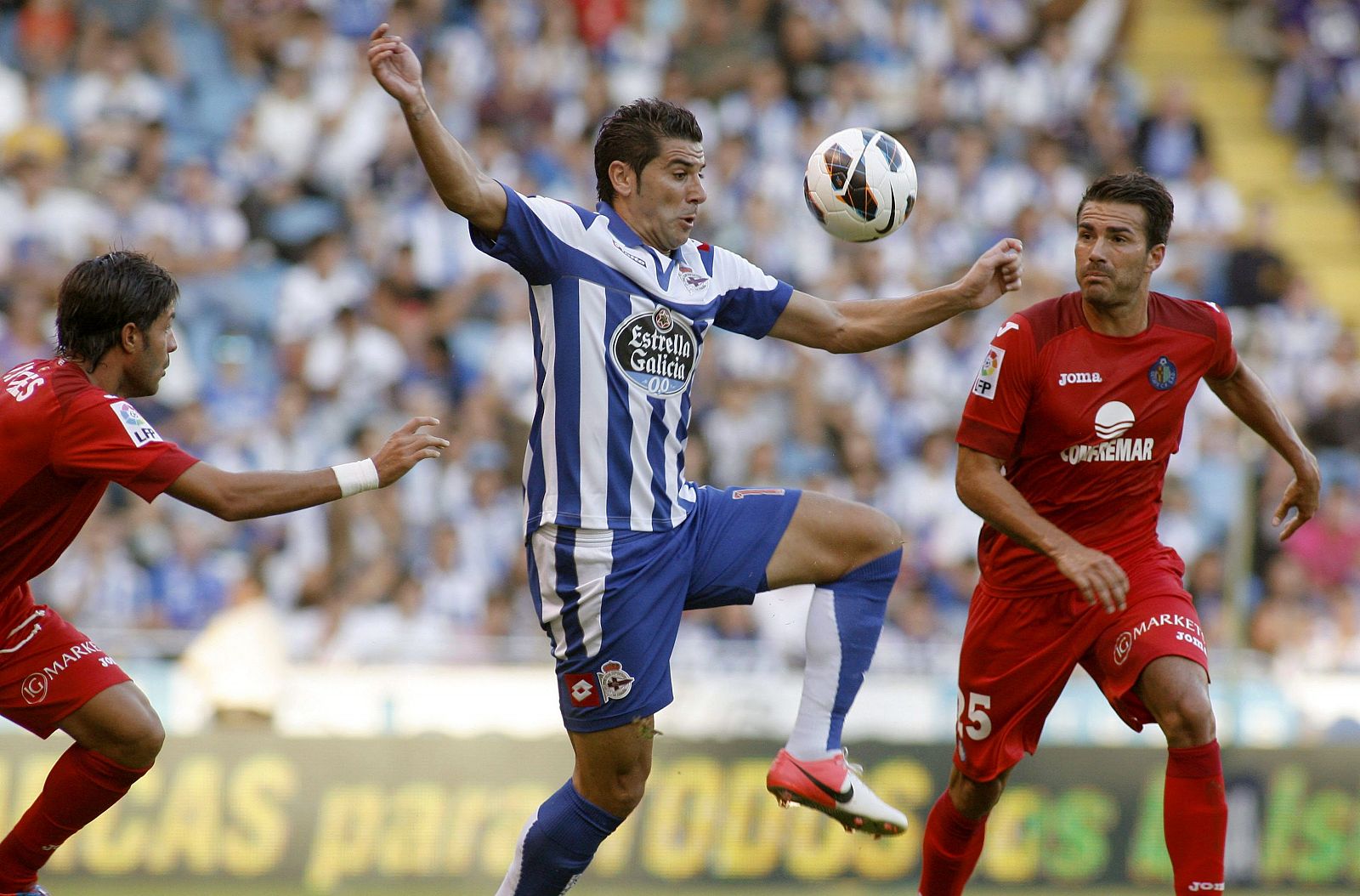 El delantero del Deportivo Iván Sánchez-Rico "Riki" (c), lucha la pelota con el centrocampista del Getafe CF, Xavi Torres (d)