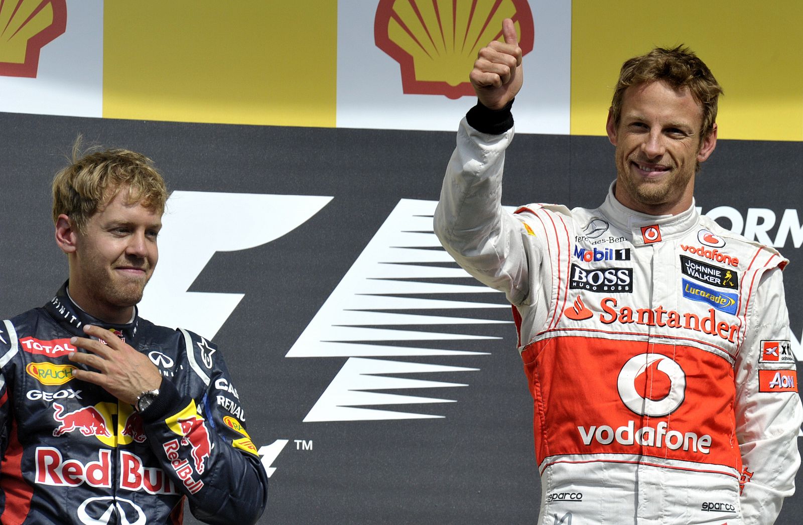 El británico Jenson Button (izq.), en el podio de Spa junto a Sebastian Vettel