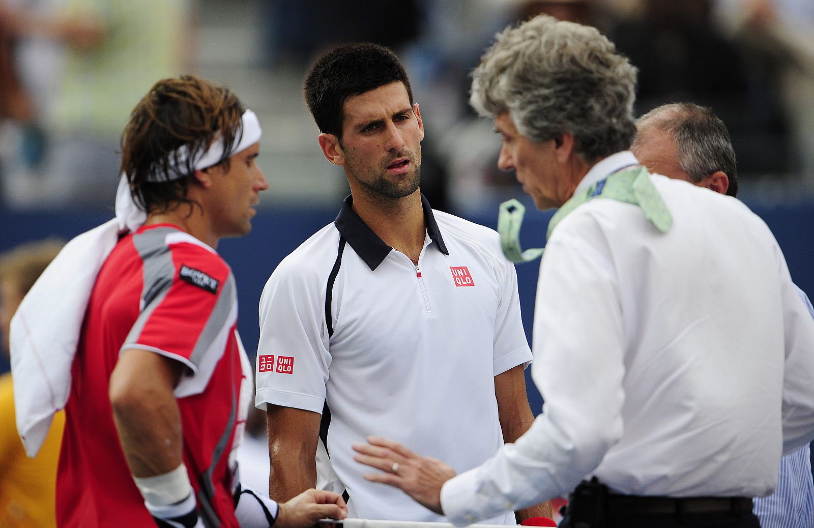El tenista español David Ferrer (i) y el serbio Novak Djokovic (c) hablan con el árbitro Brian Earley (d) quien les dice que su partido semifinal del abierto de tenis de EEUU se aplaza para el domingo.