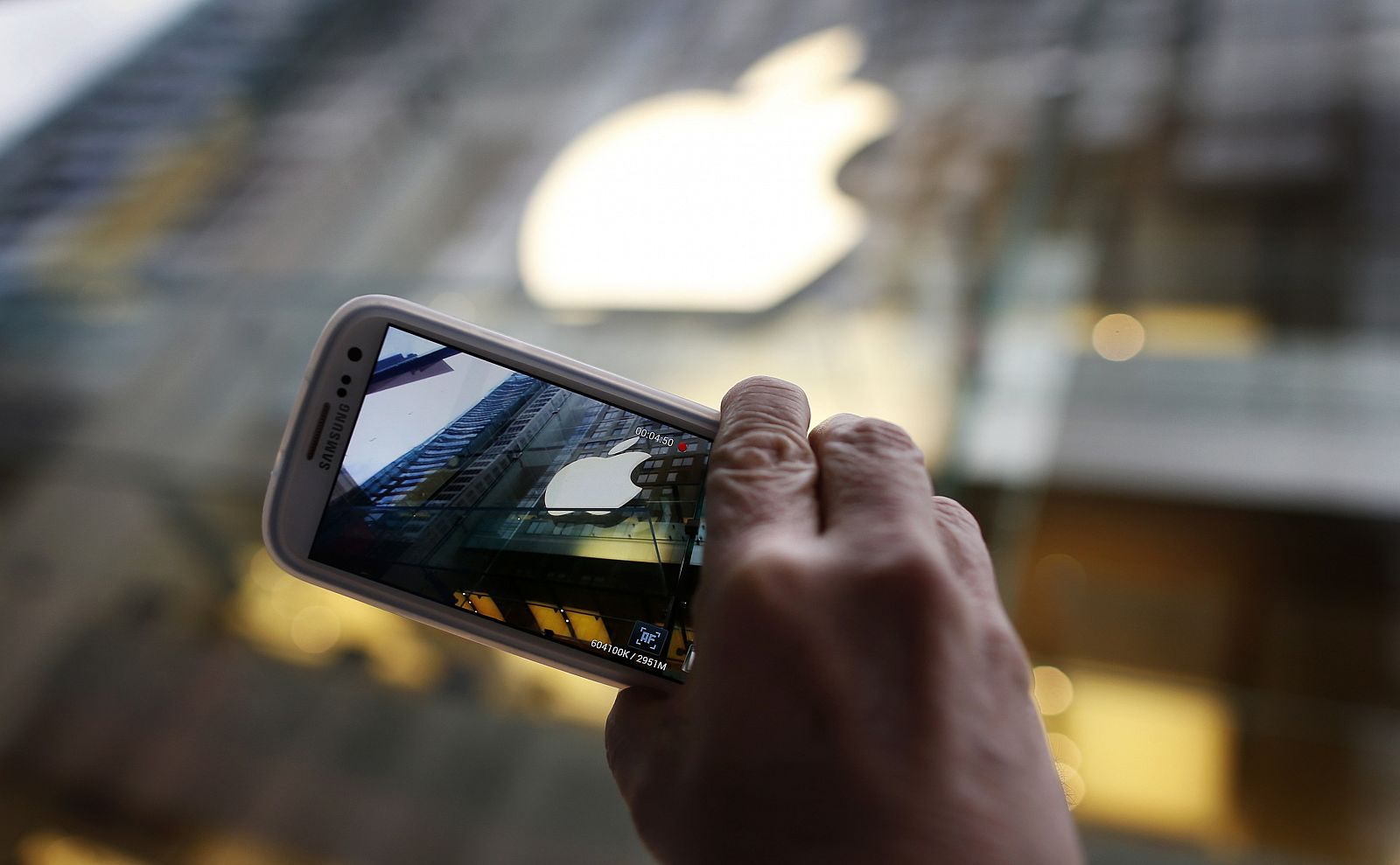 Passerby photographs Apple store logo with his Samsung Galaxy phone in central Sydney