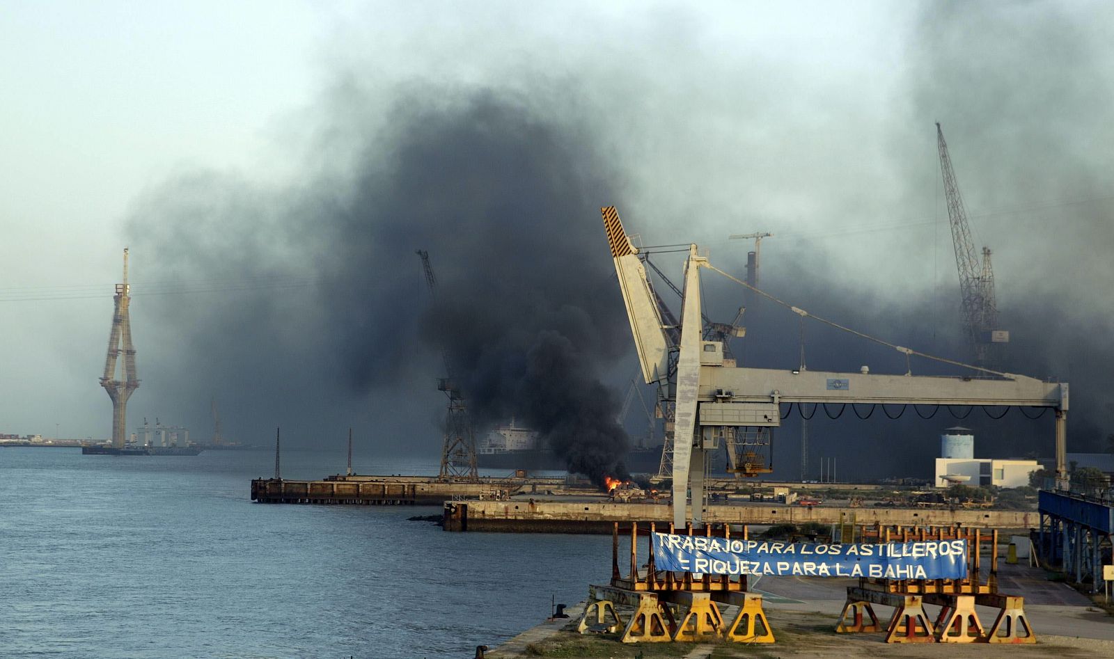 Trabajadores de los astilleros de Cádiz han prendido fuego a unos neumáticos para llamar la atención con motivo de la Cumbre Iberoamericana.